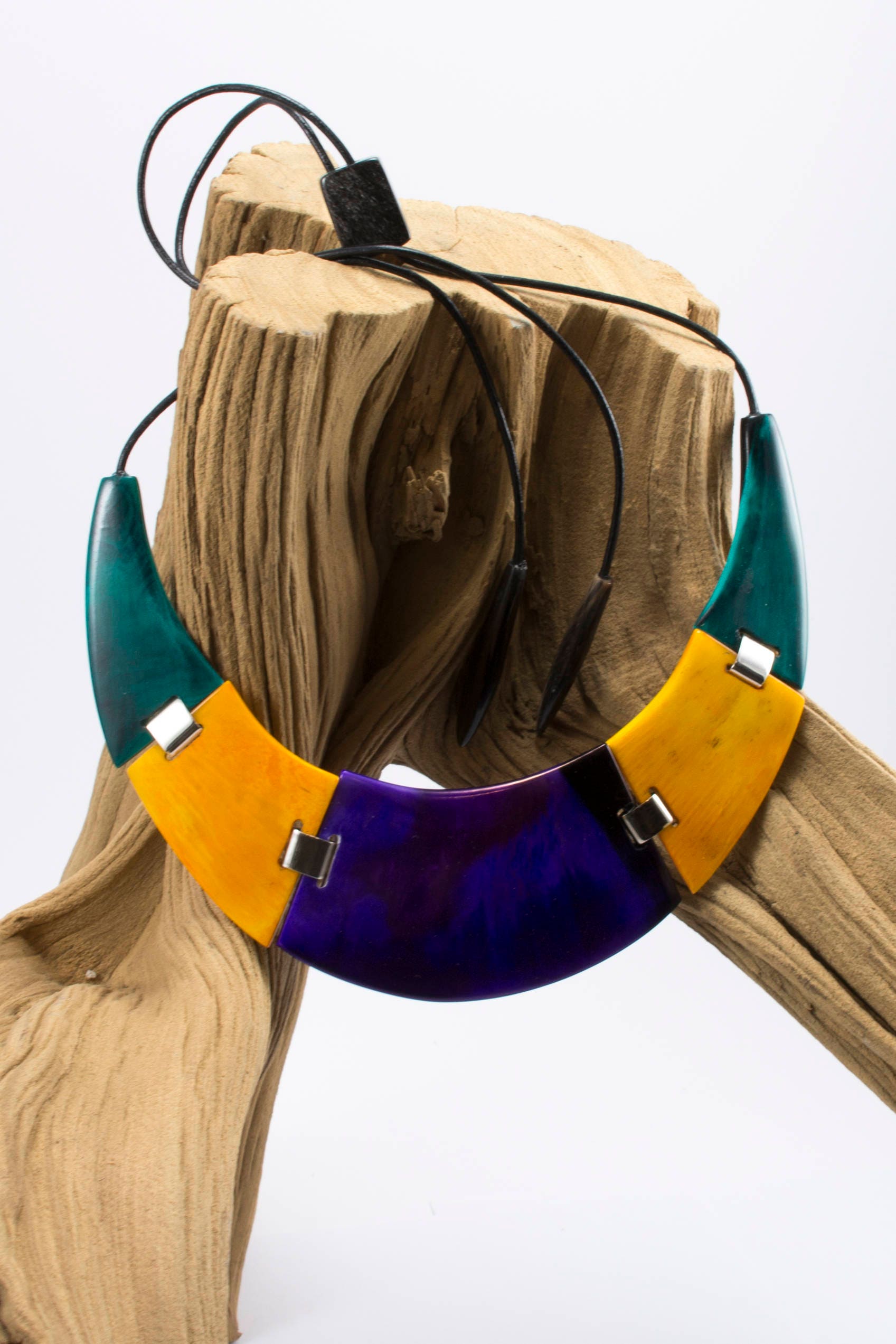 A beautifully crafted Cow Horn Necklace featuring a half-moon design with vibrant colors and silver elements, elegantly displayed on a neutral background.