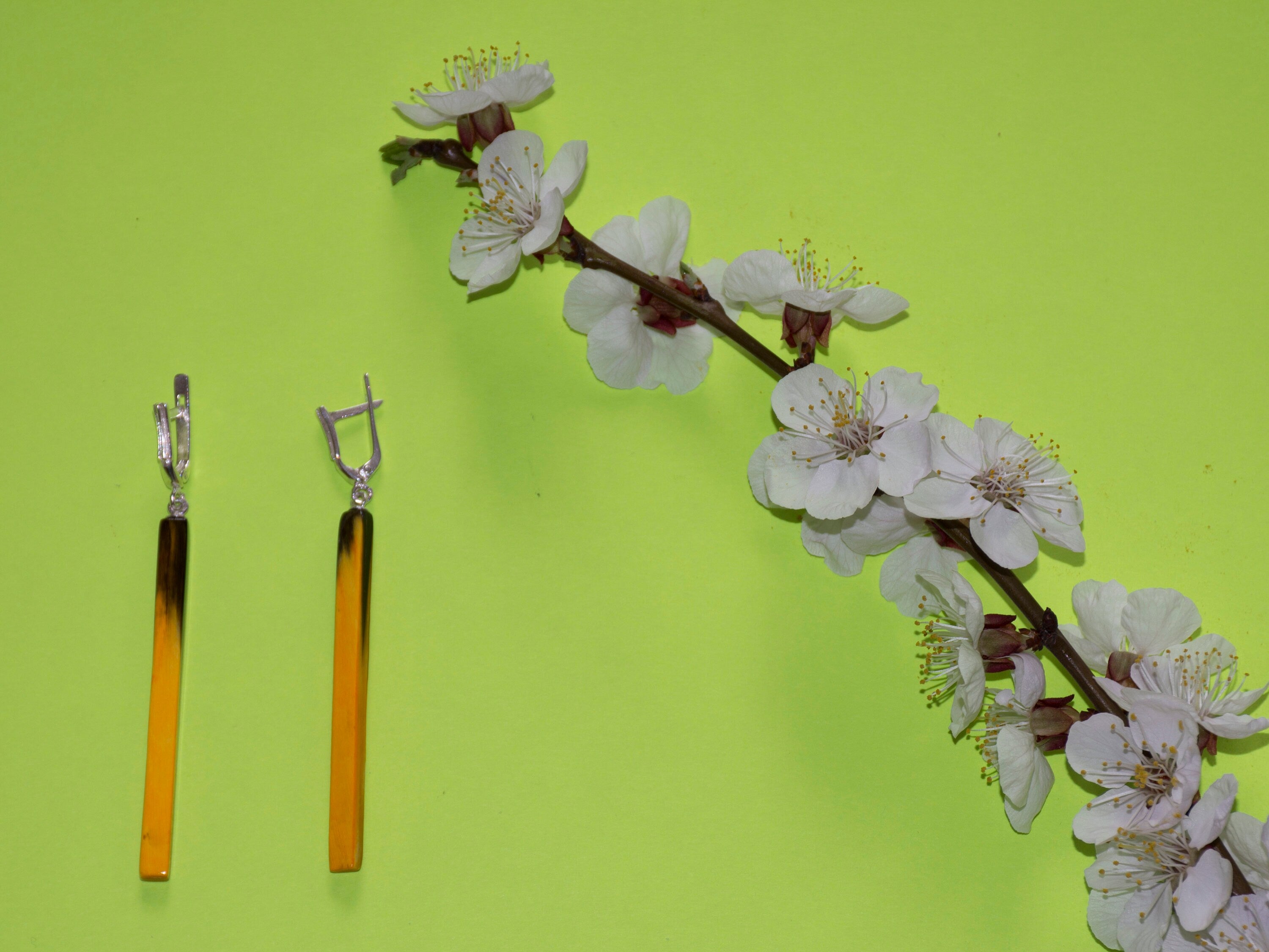 A pair of handmade neon yellow earrings made from natural buffalo horn with a polished surface and silver English locks, showcasing a unique geometric design.