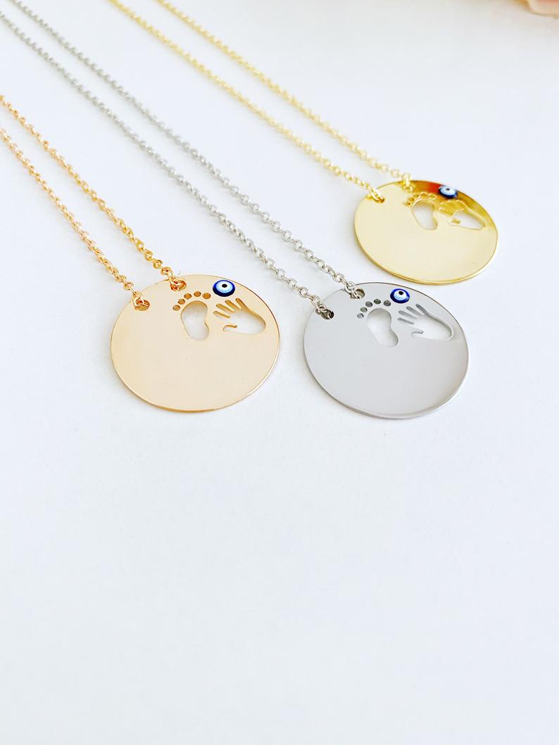 New Baby Necklace featuring an Evil Eye design with baby feet and handprint motifs, available in gold, silver, and rose gold.