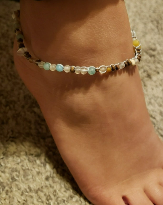 Nixie Beaded Anklet featuring natural stones, shells, and sea-glass beads, elegantly displayed on a soft surface.