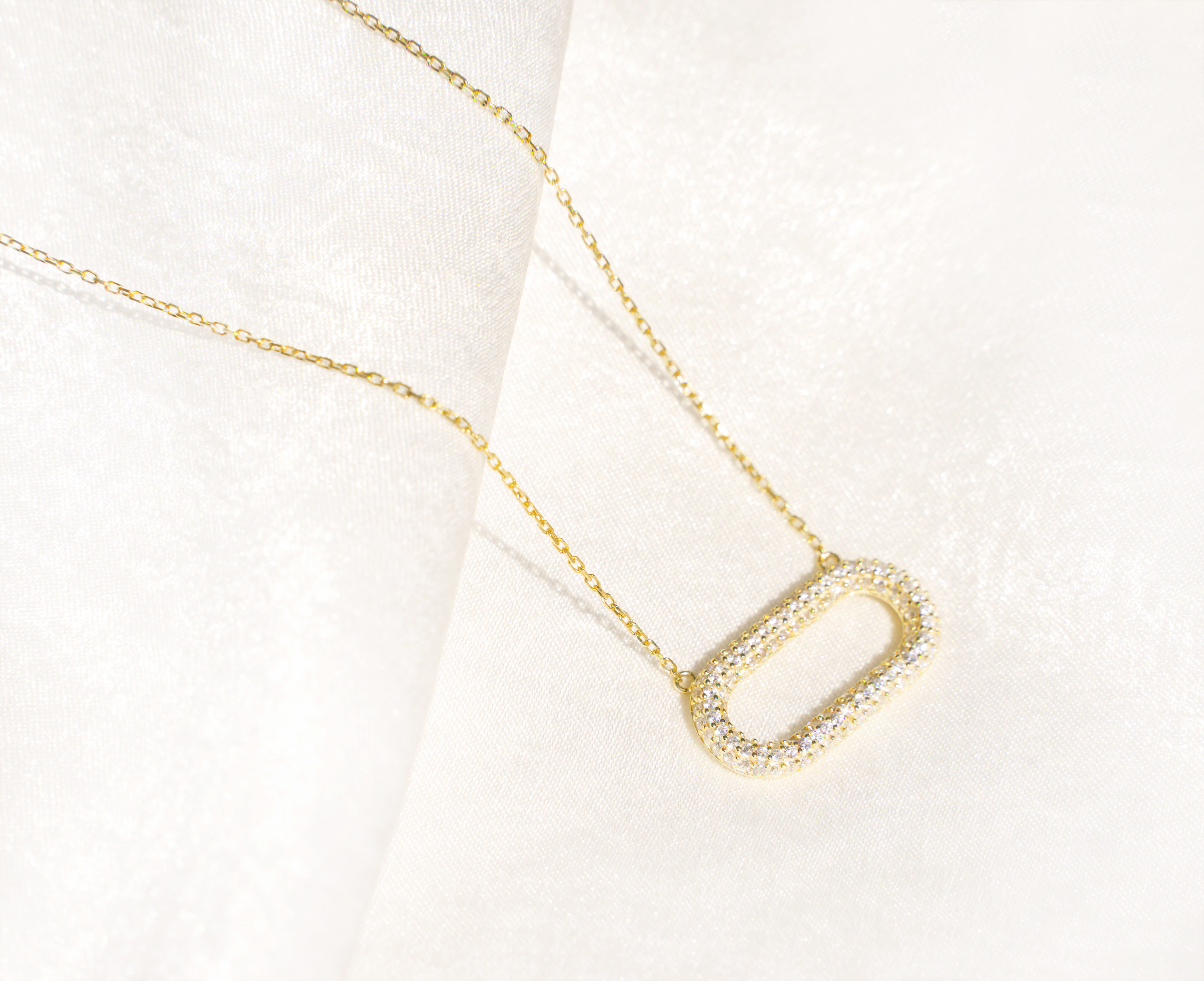 NOOR Oval Necklace featuring cubic zirconias on a yellow gold plated sterling silver chain, elegantly displayed.