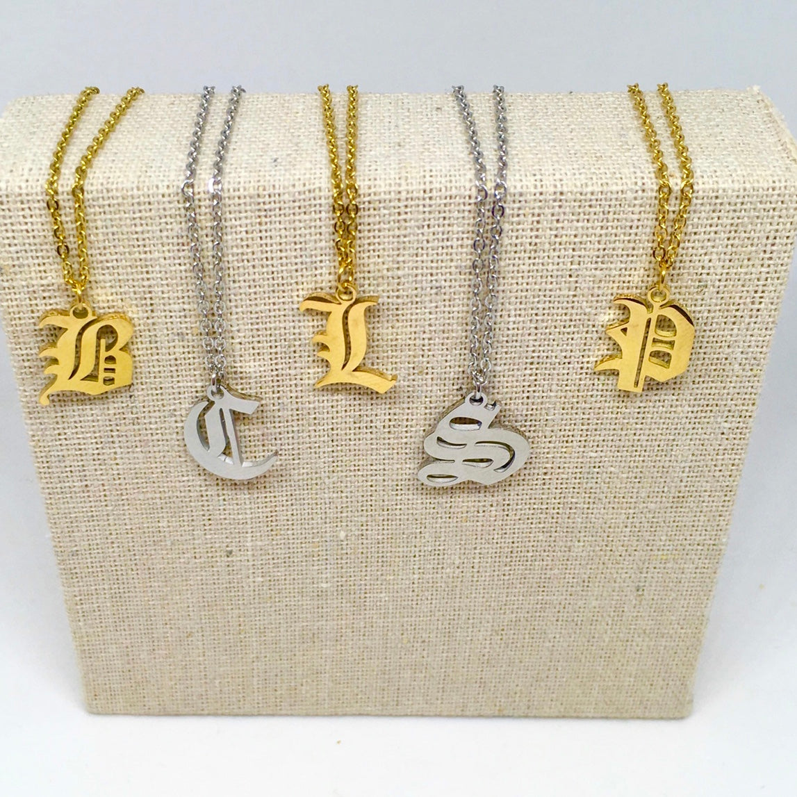 A stylish Old English Initial Necklace made of stainless steel, featuring a personalized initial pendant and a 50cm chain, available in various colors.