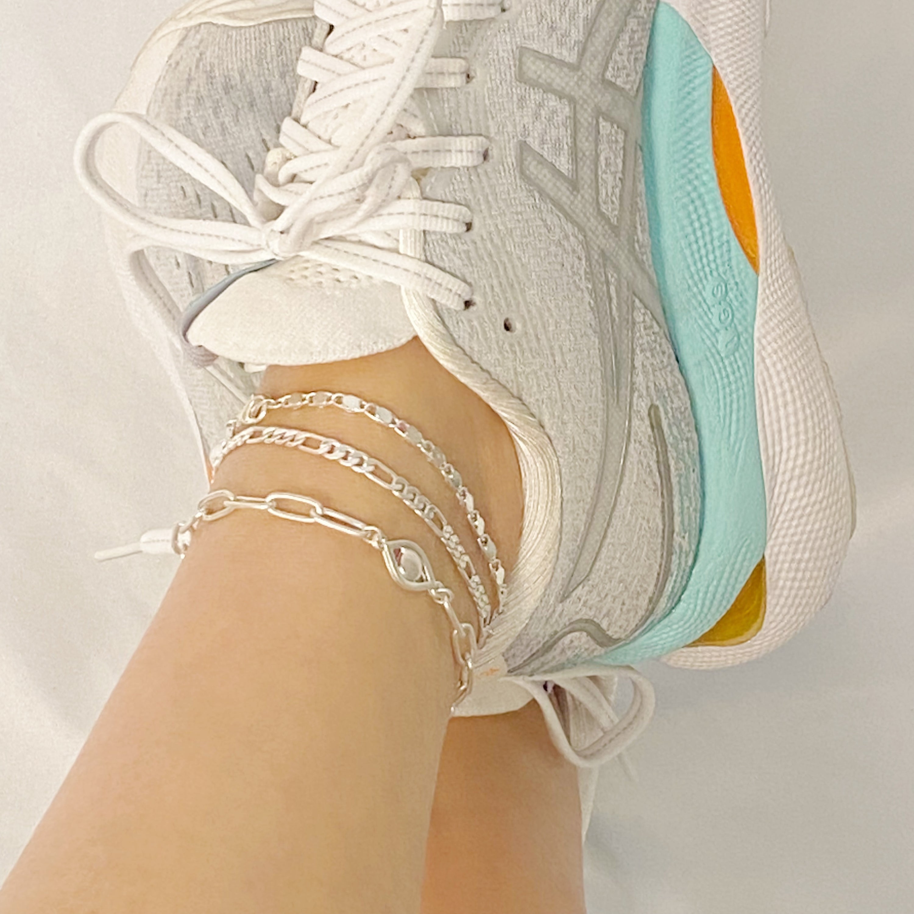 Set of three trendy chain anklets, featuring unique designs and adjustable lengths, perfect for layering or wearing alone.