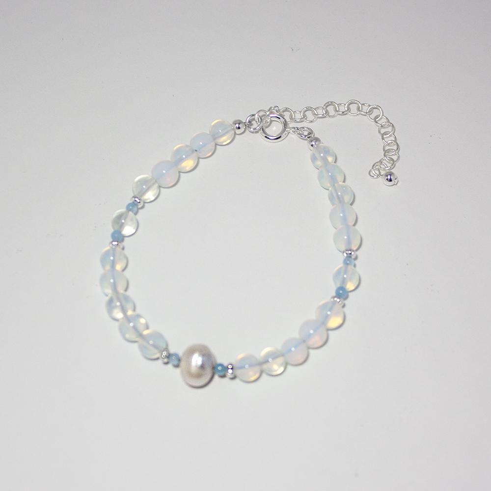 A beautiful bracelet featuring opalite beads and freshwater pearls, showcasing a shimmering design with a silver-plated brass closure.