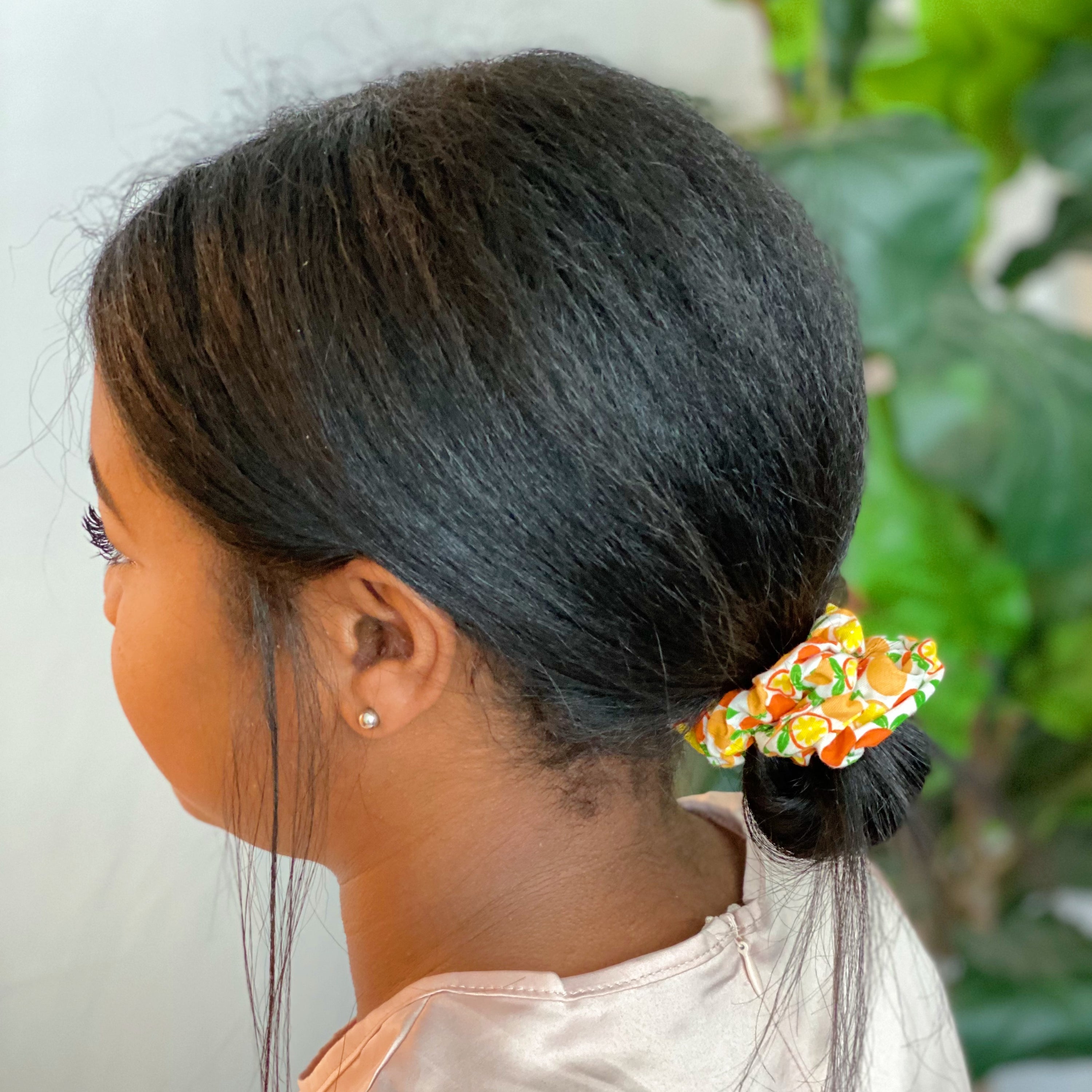 A set of four colorful hair scrunchies featuring two fruit prints and two solid colors, neatly arranged in a clear cello case.