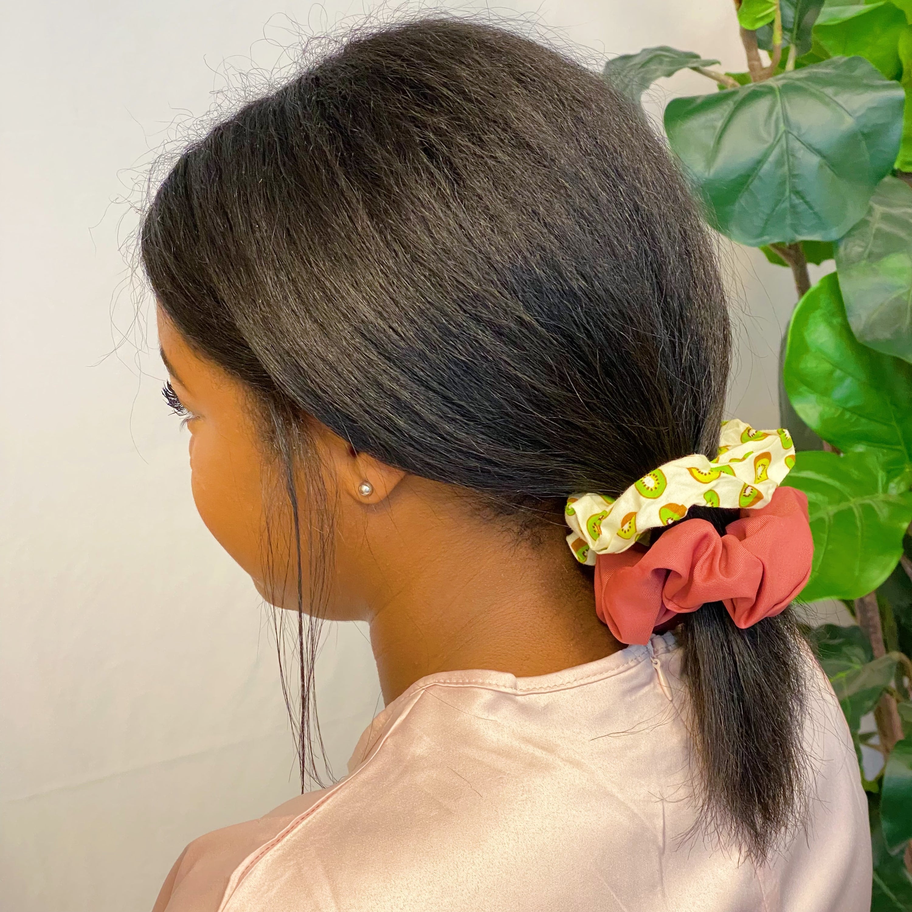 A set of four colorful hair scrunchies featuring two fruit prints and two solid colors, neatly arranged in a clear cello case.