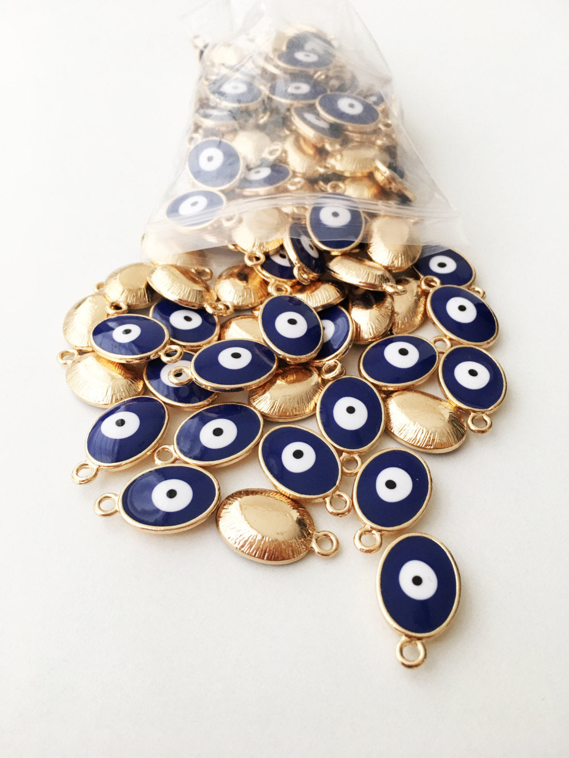 Set of 5 oval blue evil eye charms made of brass with enamel finish, showcasing intricate designs for jewelry making.