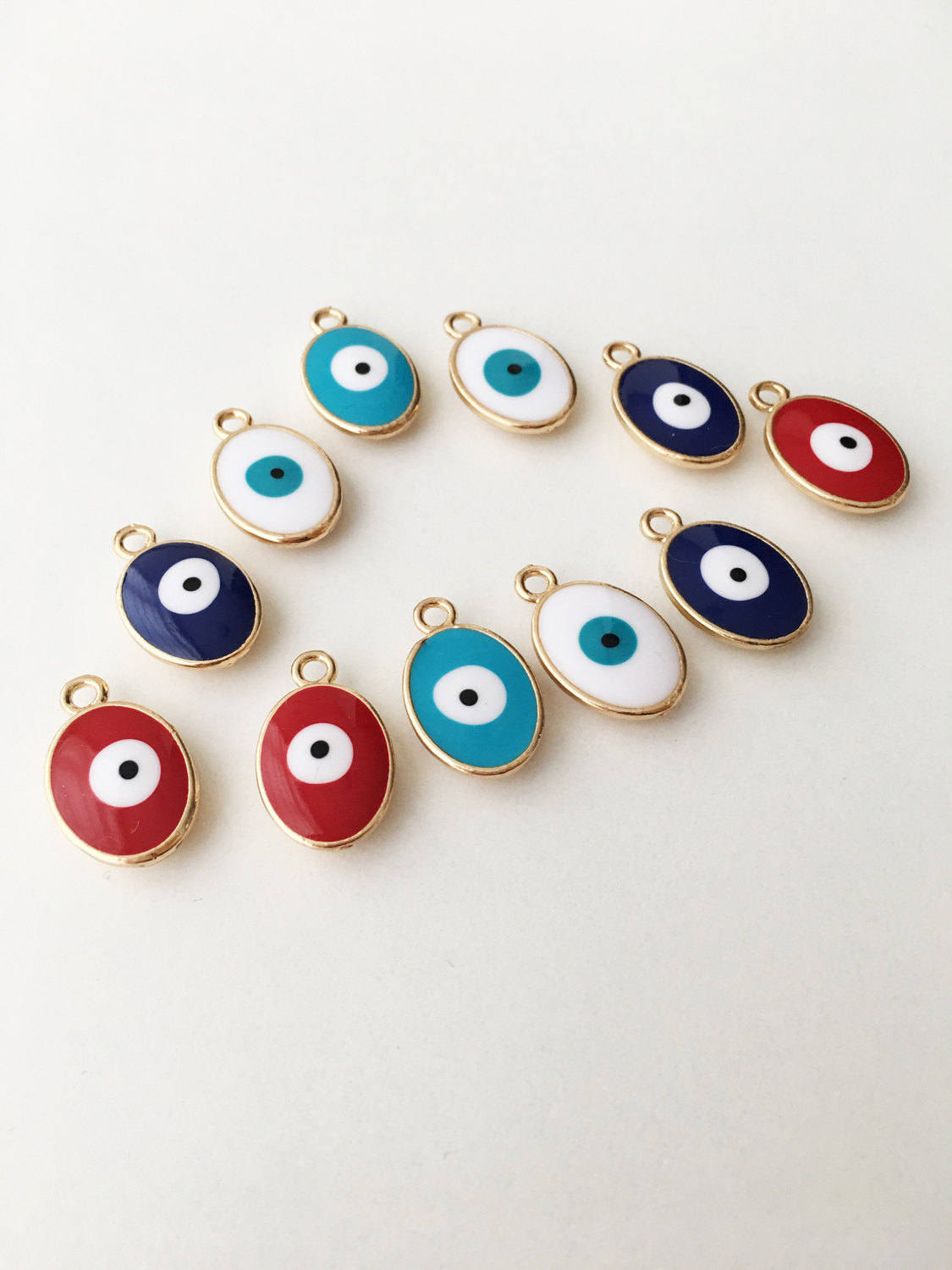 Set of 5 oval blue evil eye charms made of brass with enamel finish, showcasing intricate designs for jewelry making.