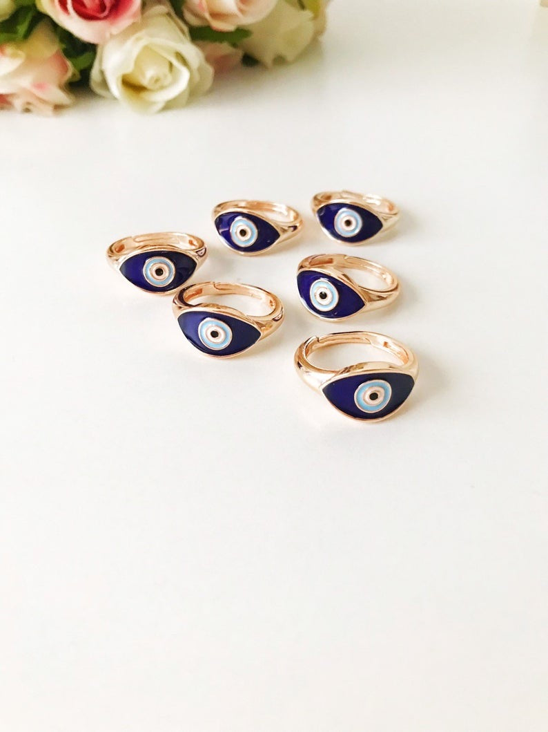 A beautiful adjustable Oval Evil Eye Ring featuring a blue or white evil eye bead set in a delicate rose gold design.