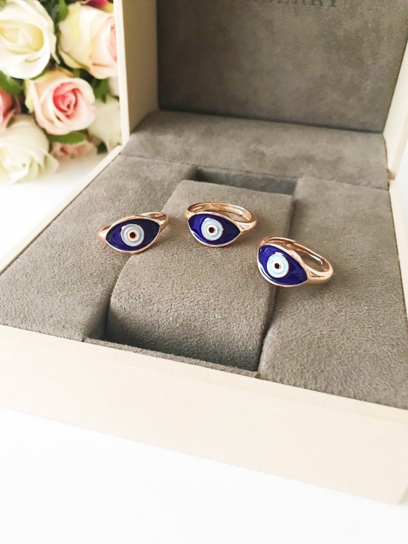 A beautiful adjustable Oval Evil Eye Ring featuring a blue or white evil eye bead set in a delicate rose gold design.