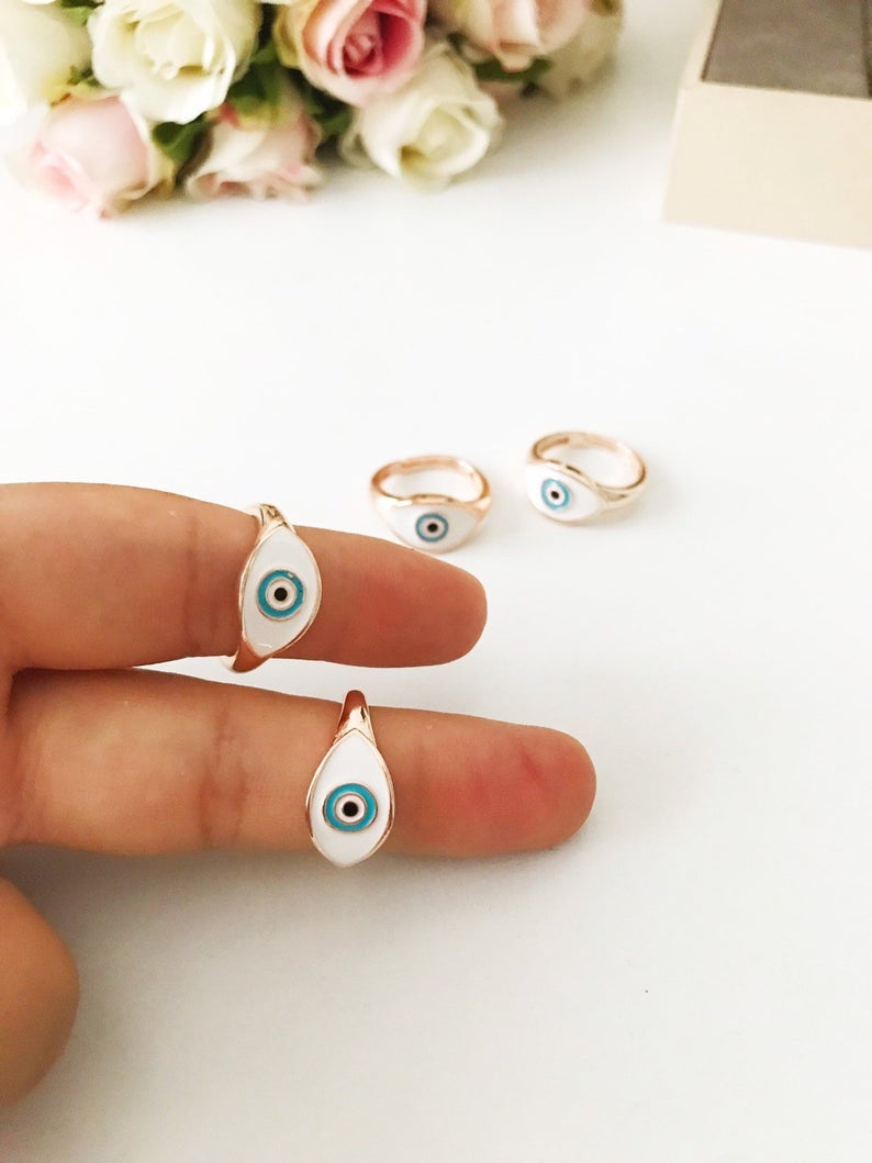 A beautiful adjustable Oval Evil Eye Ring featuring a blue or white evil eye bead set in a delicate rose gold design.