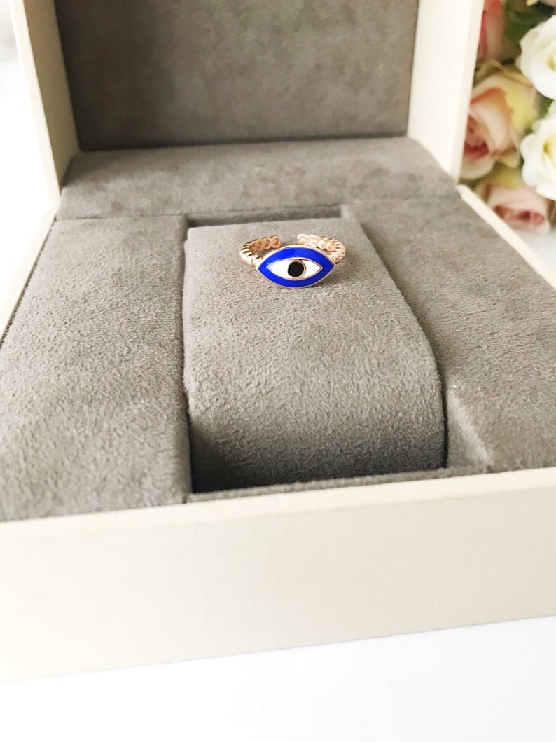 A beautiful oval evil eye ring featuring a blue evil eye bead set in rose gold, showcasing its adjustable design and minimalist style.