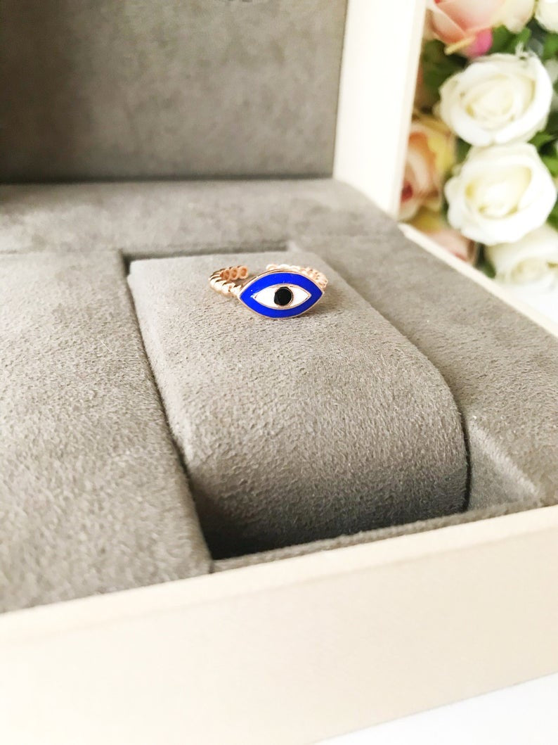 A beautiful oval evil eye ring featuring a blue evil eye bead set in rose gold, showcasing its adjustable design and minimalist style.