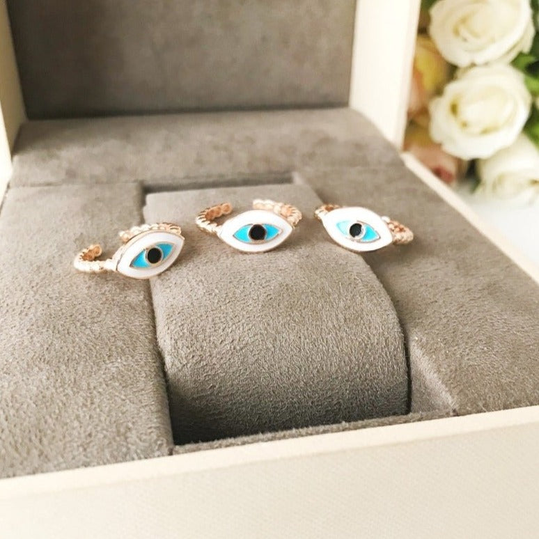 A stylish oval rose gold evil eye ring featuring a white evil eye bead, adjustable design for comfort, and minimalist elegance.