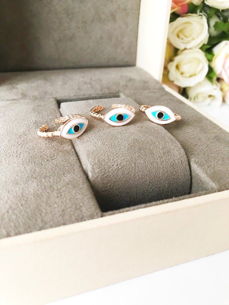 A stylish oval rose gold evil eye ring featuring a white evil eye bead, adjustable design for comfort, and minimalist elegance.