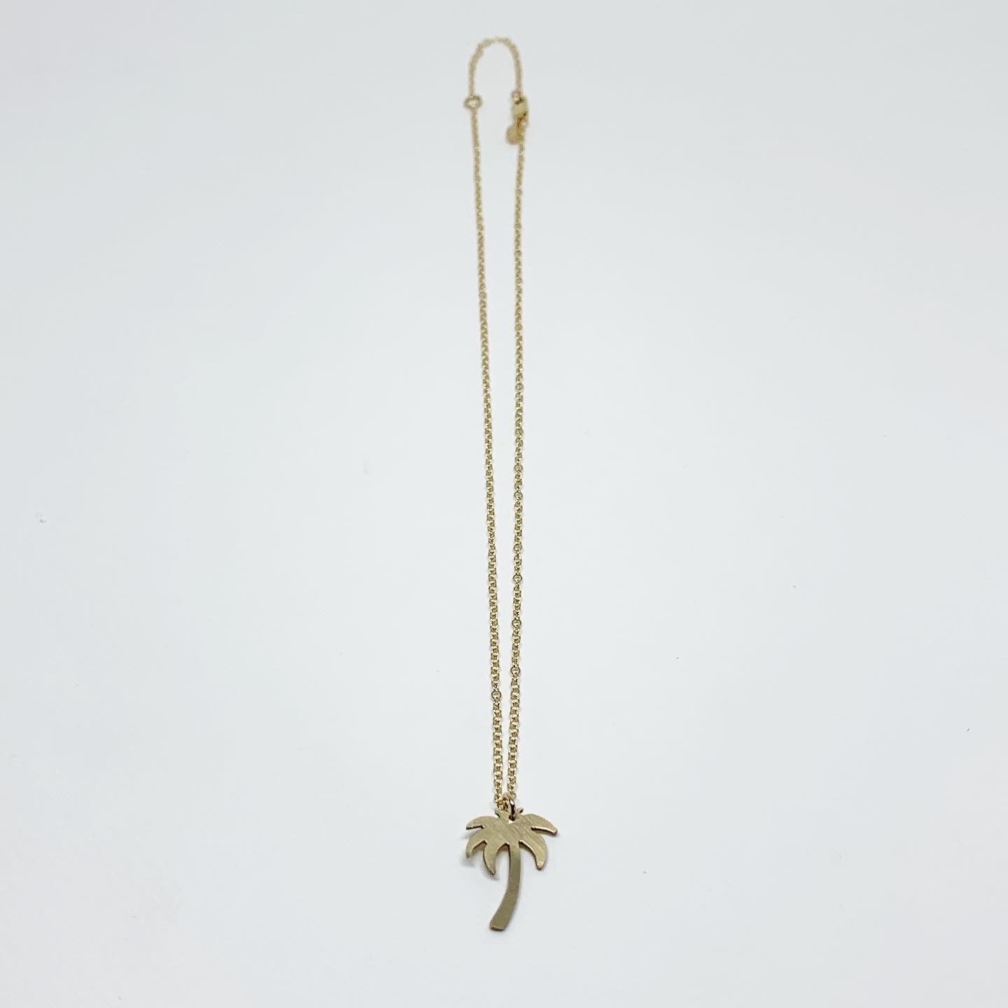 A delicate Palm Tree Charm Necklace featuring a hand-cut palm tree pendant in recycled sterling silver, displayed on a lightweight adjustable chain.