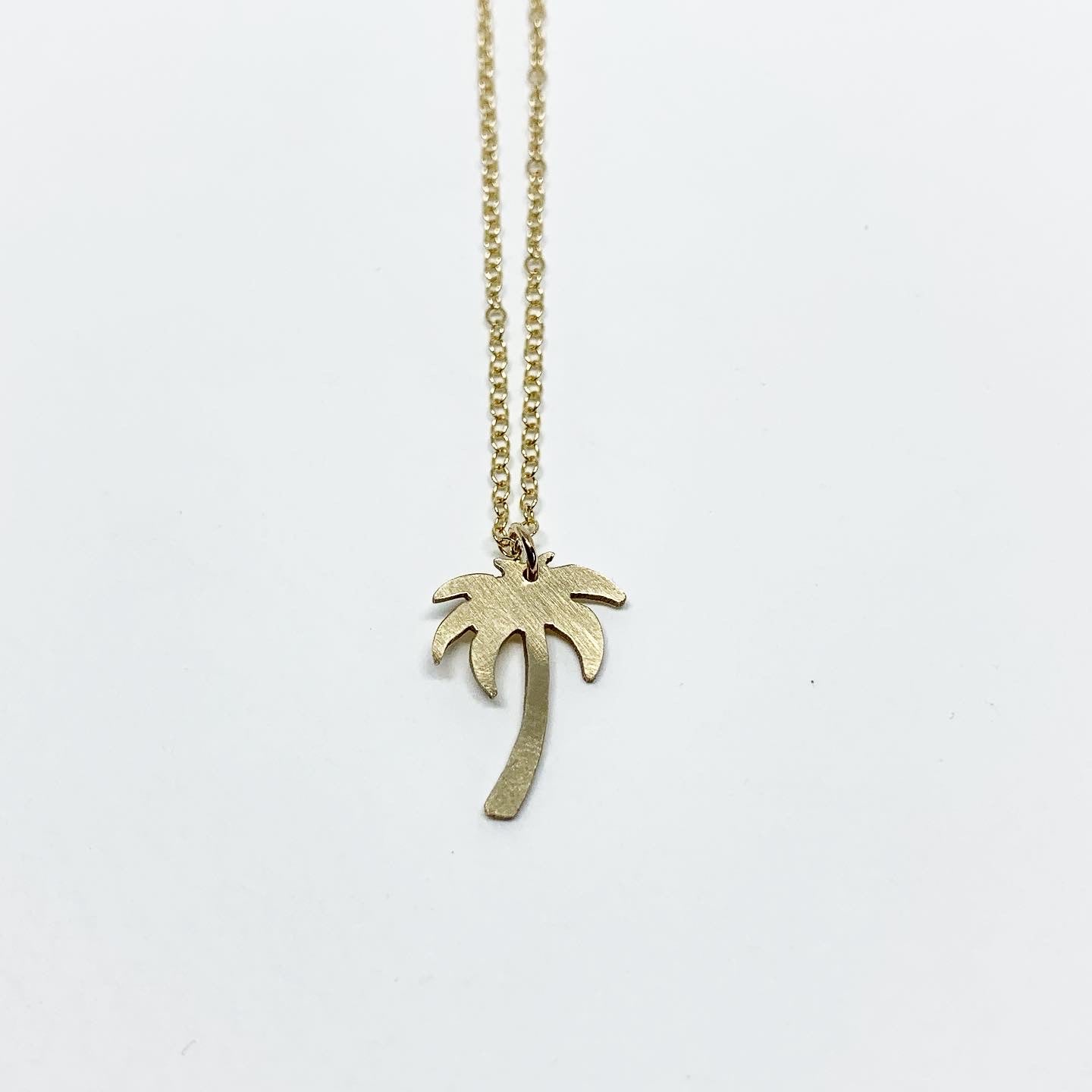 A delicate Palm Tree Charm Necklace featuring a hand-cut palm tree pendant in recycled sterling silver, displayed on a lightweight adjustable chain.