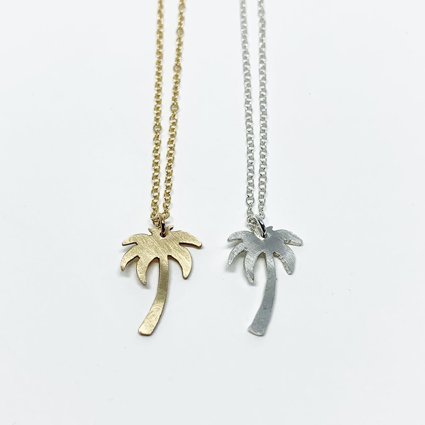 A delicate Palm Tree Charm Necklace featuring a hand-cut palm tree pendant in recycled sterling silver, displayed on a lightweight adjustable chain.