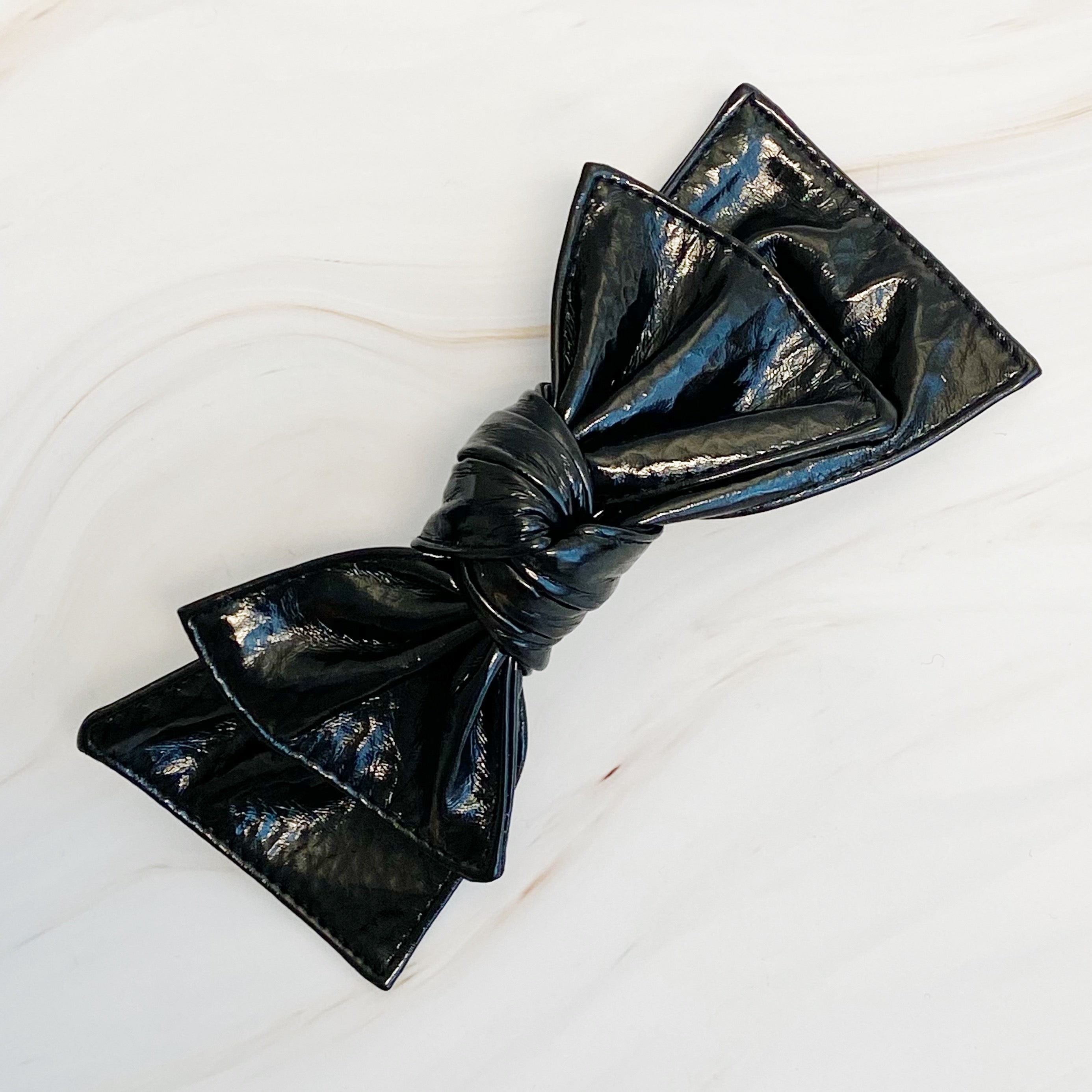 Patent Double Bow Hair Clip in faux patent leather, featuring a stylish double bow design, perfect for various hairstyles.