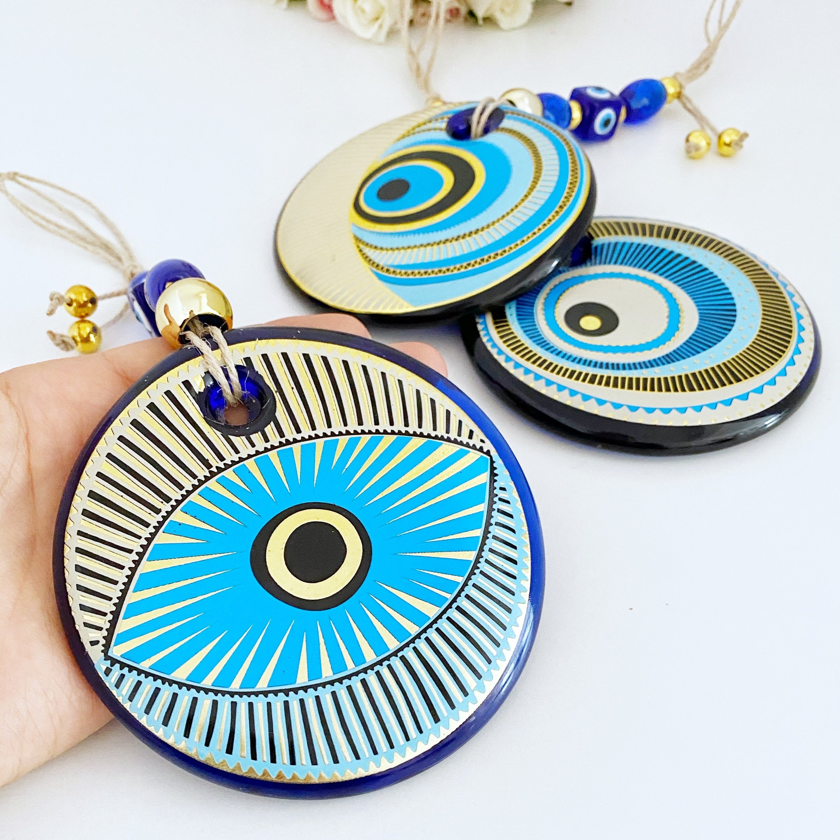 A beautifully painted blue evil eye wall hanging featuring intricate patterns, perfect for home decor and protection.