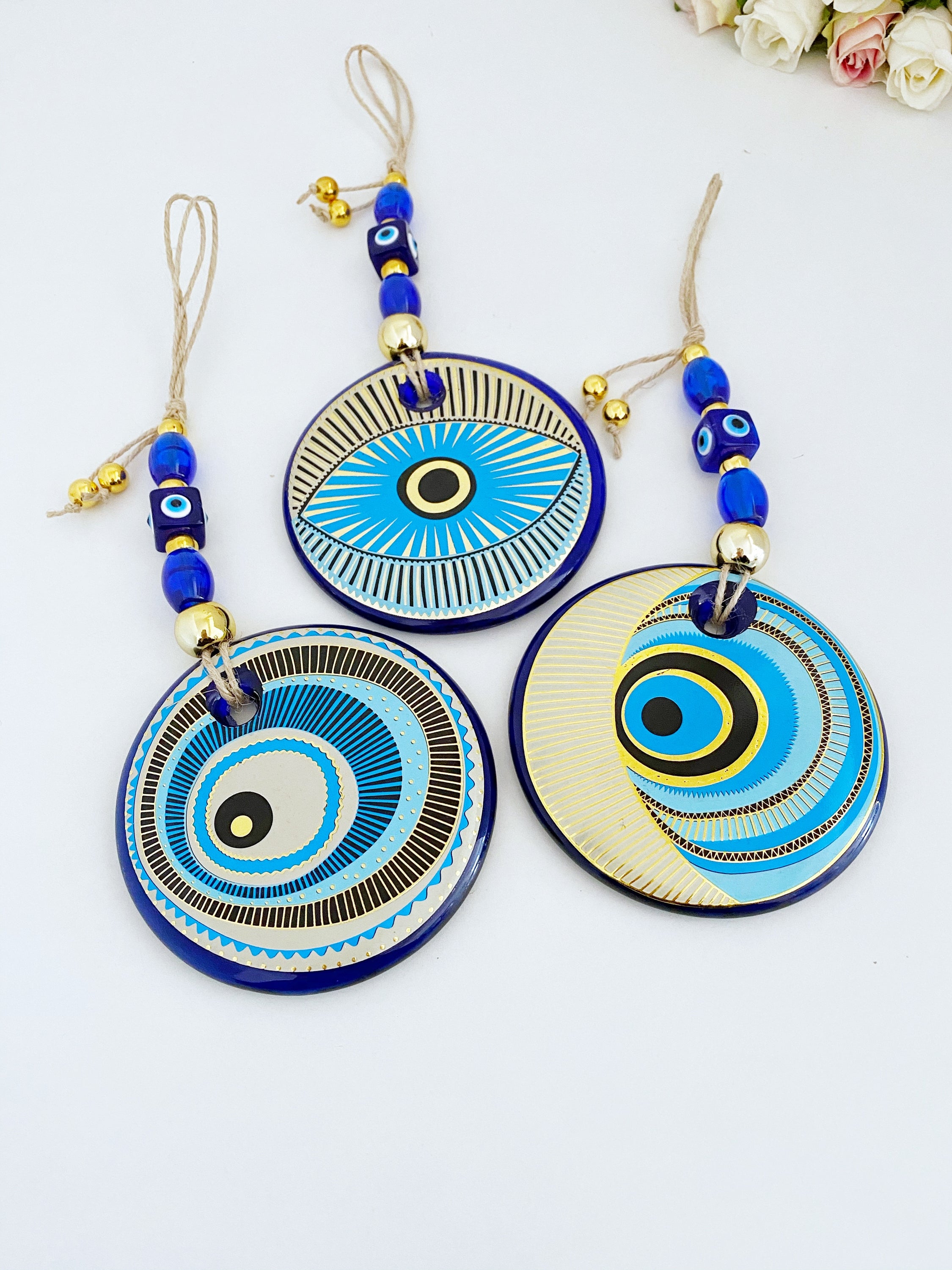 A beautifully painted blue evil eye wall hanging featuring intricate patterns, perfect for home decor and protection.