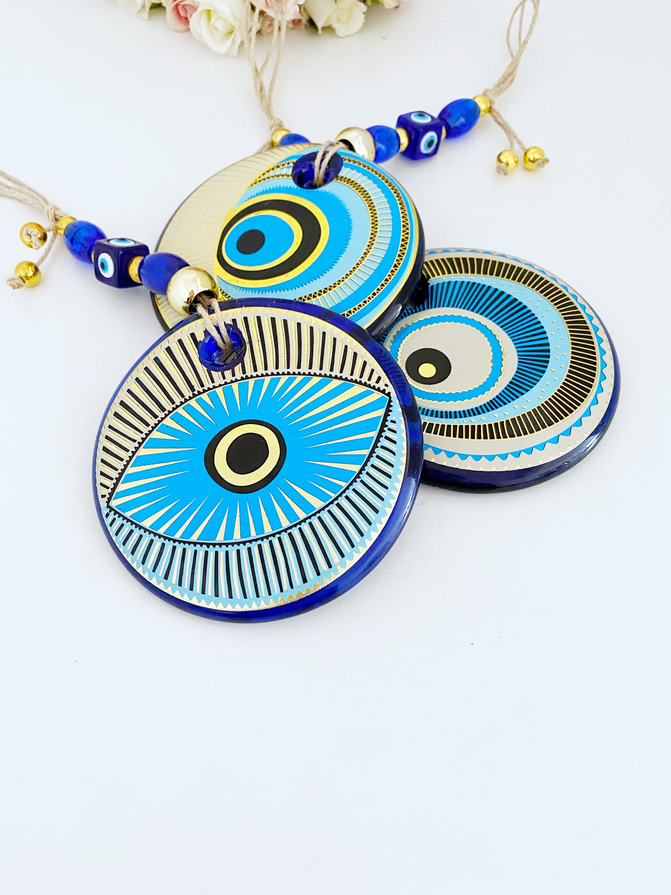 A beautifully painted blue evil eye wall hanging featuring intricate patterns, perfect for home decor and protection.