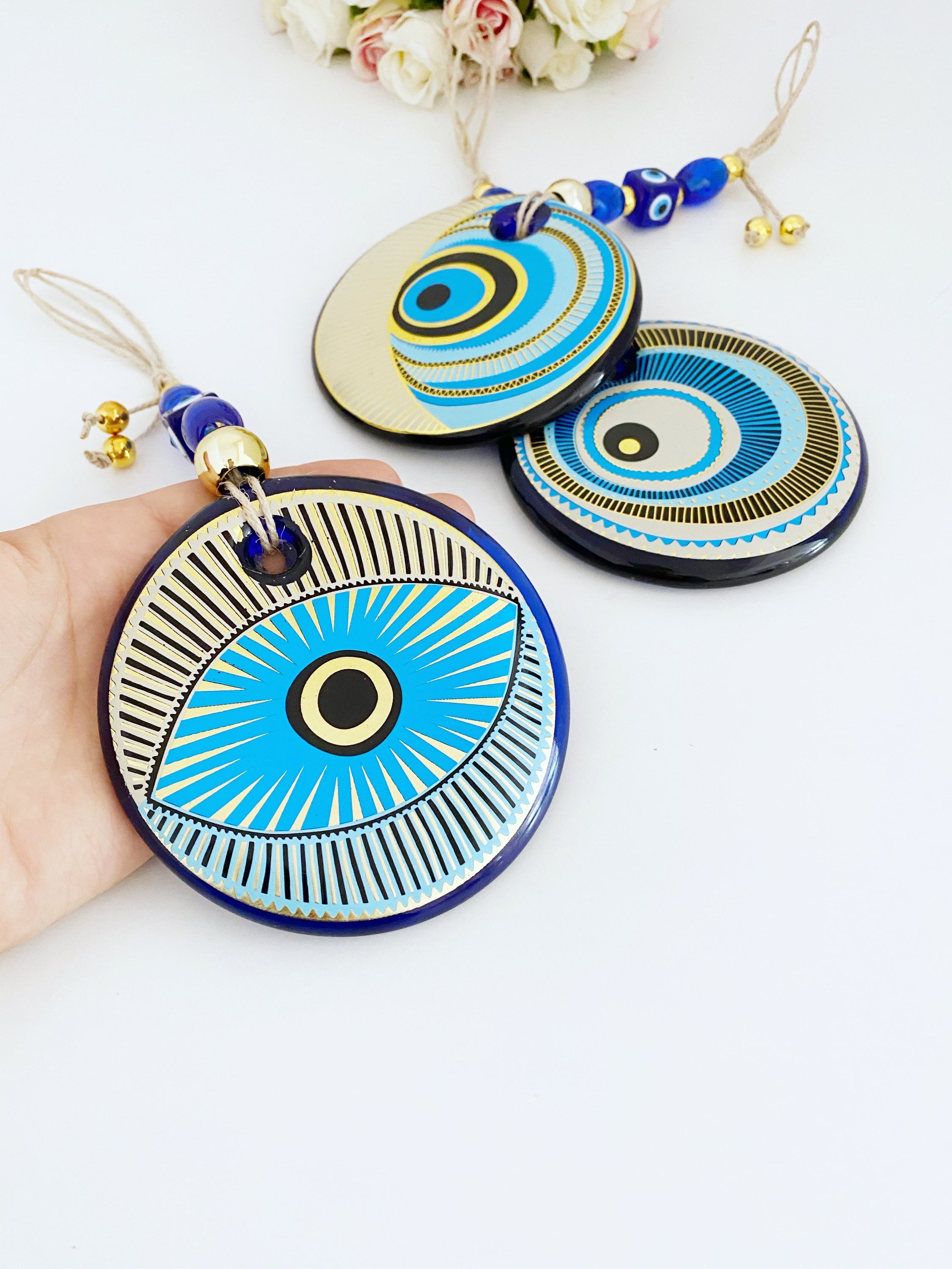 A beautifully painted blue evil eye wall hanging featuring intricate patterns, perfect for home decor and protection.