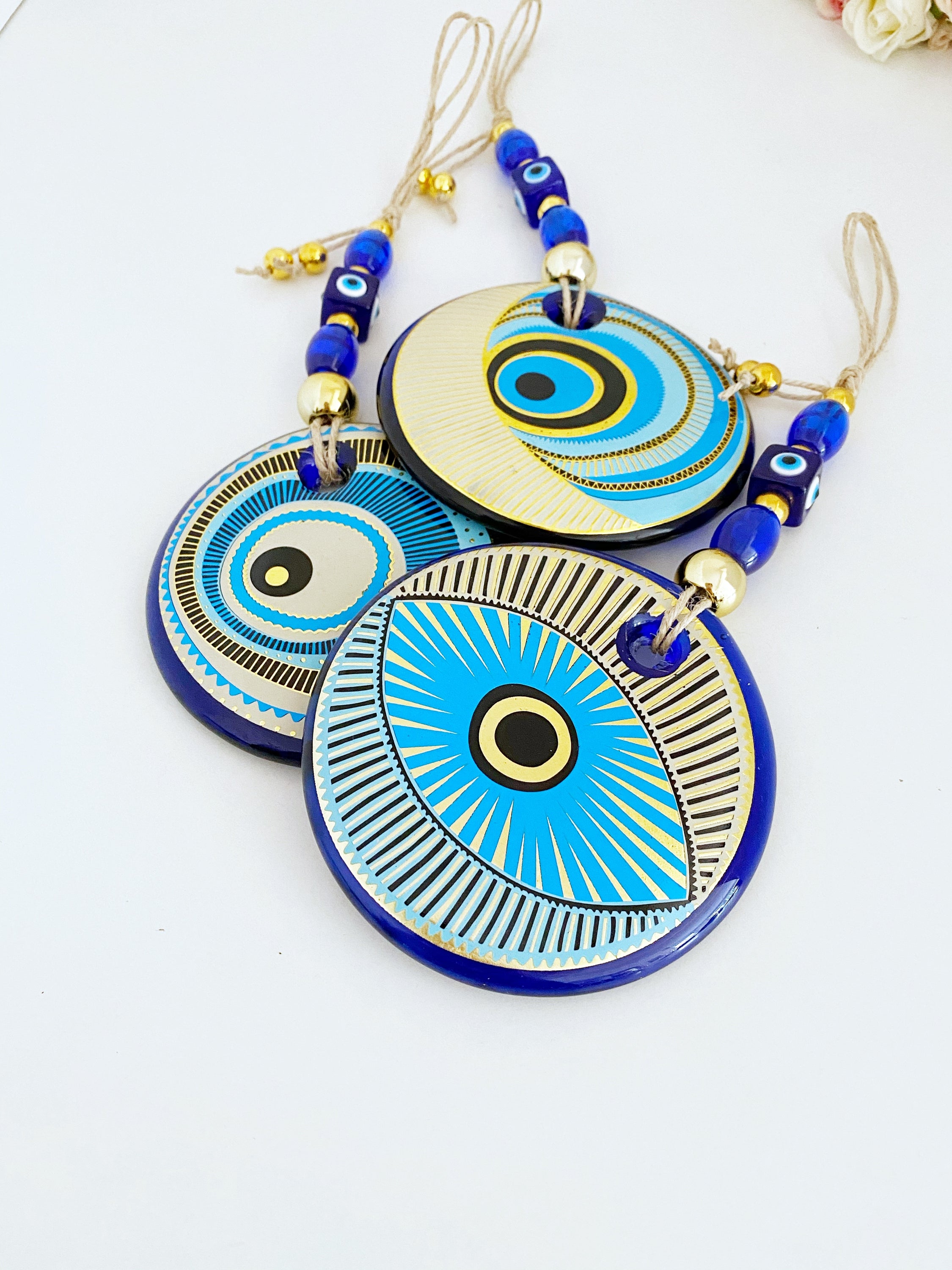 A beautifully painted blue evil eye wall hanging featuring intricate patterns, perfect for home decor and protection.