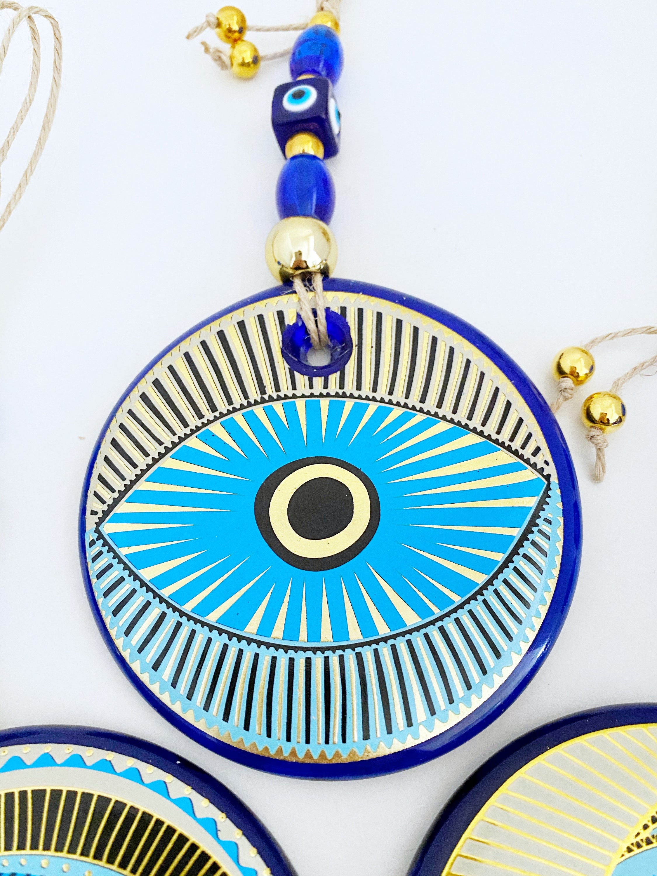 A beautifully painted blue evil eye wall hanging featuring intricate patterns, perfect for home decor and protection.