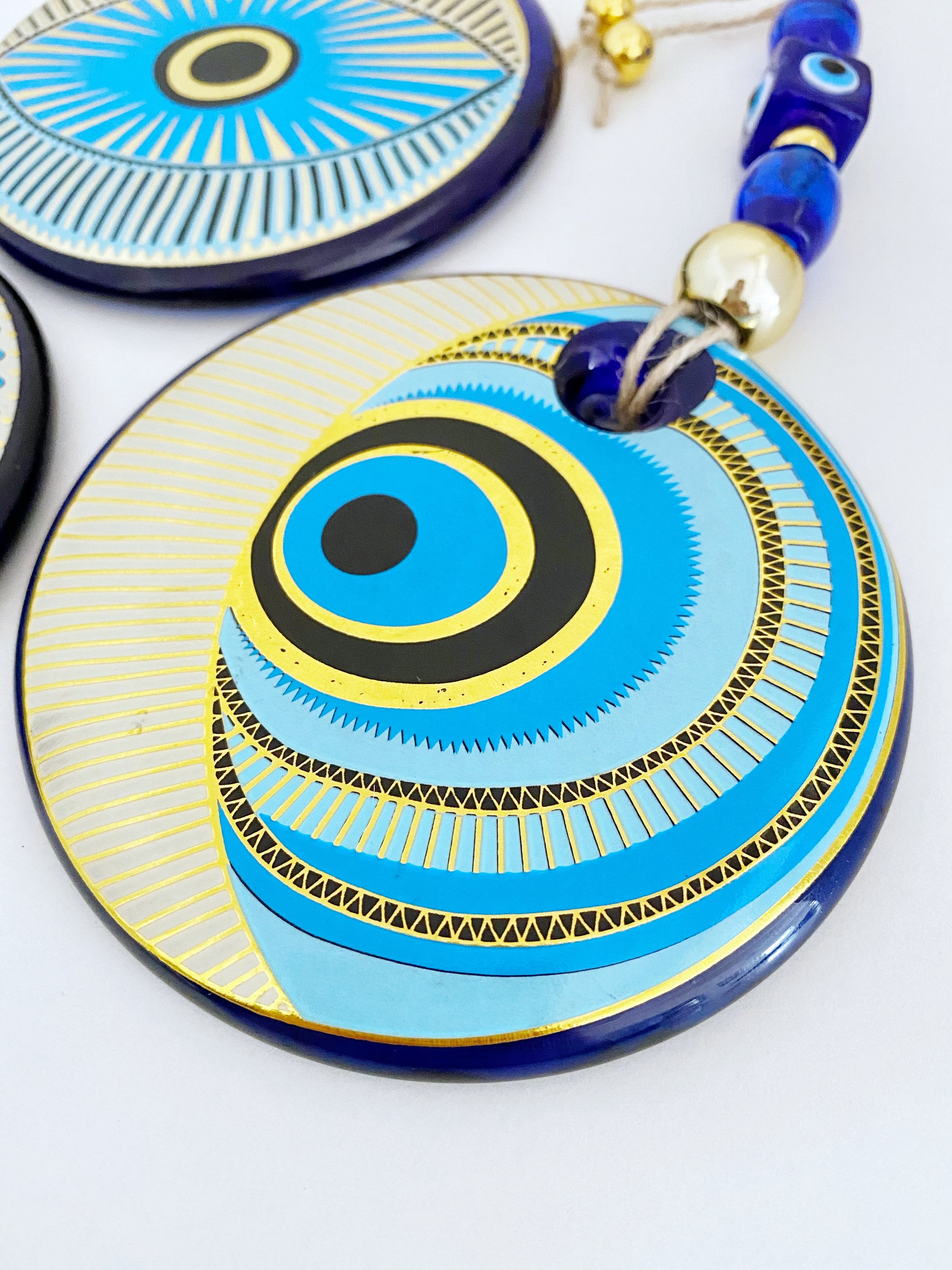 A beautifully painted blue evil eye wall hanging featuring intricate patterns, perfect for home decor and protection.