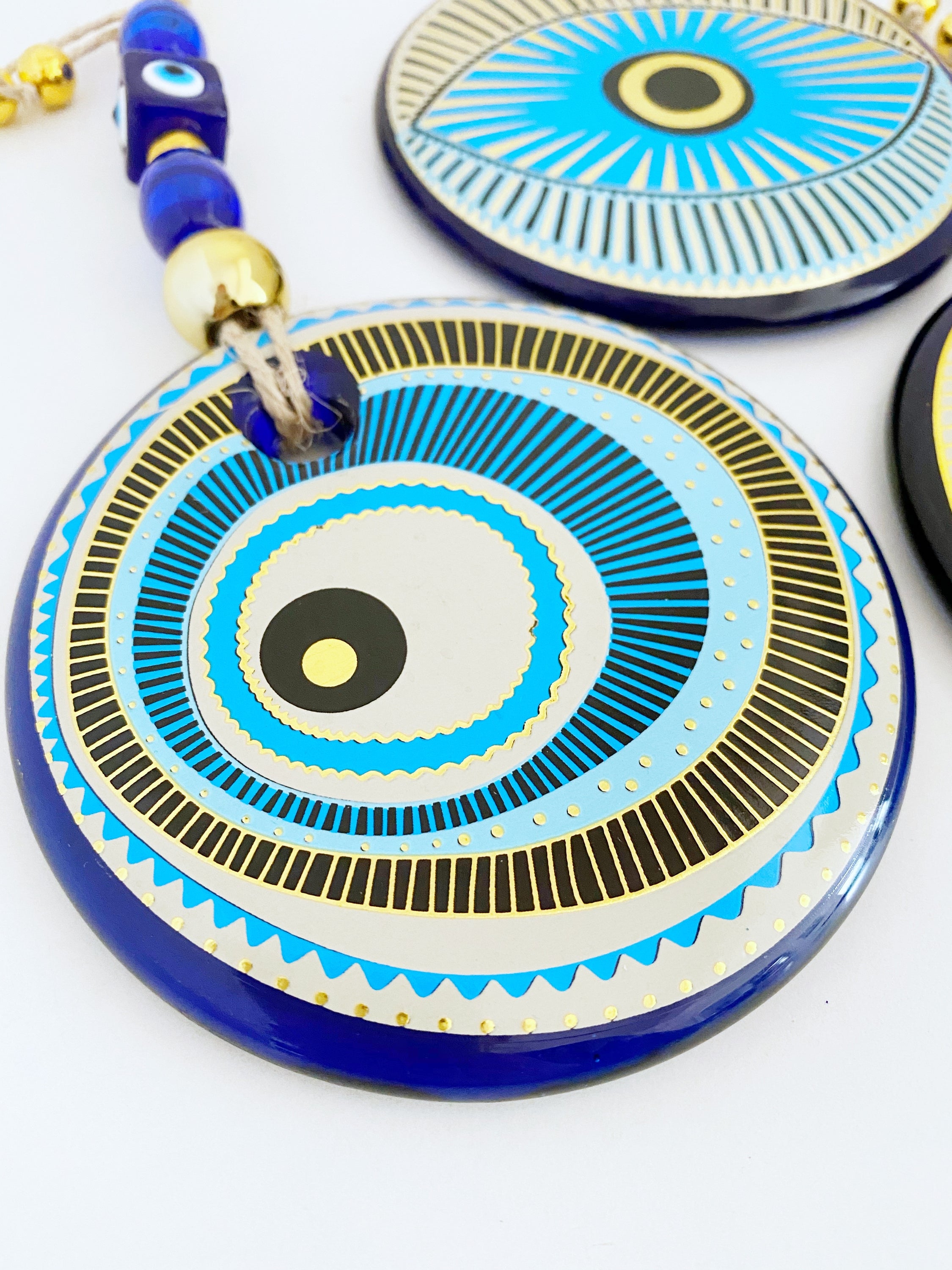 A beautifully painted blue evil eye wall hanging featuring intricate patterns, perfect for home decor and protection.