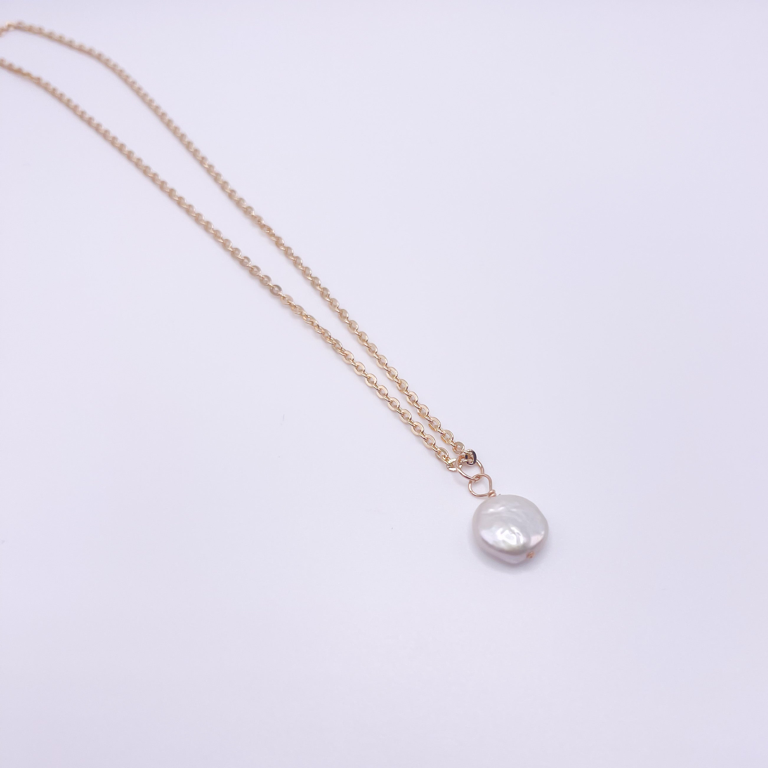 A dainty pearl necklace featuring a 12mm freshwater coin pearl on a gold filled rolo chain, showcasing elegance and handmade craftsmanship.