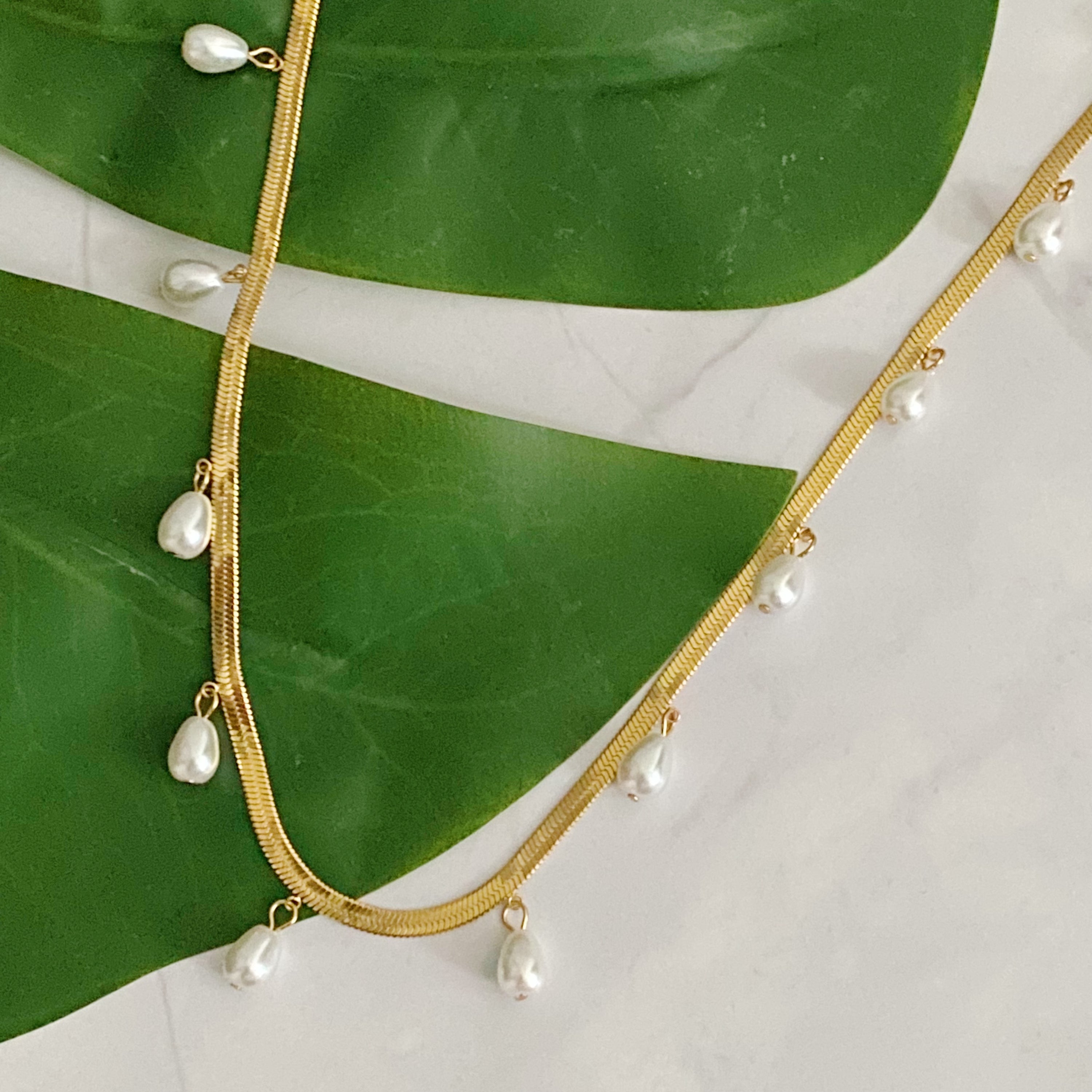 Elegant Pearl Drop Herringbone Chain Necklace featuring teardrop-shaped glass pearls on a gold plated stainless steel chain.