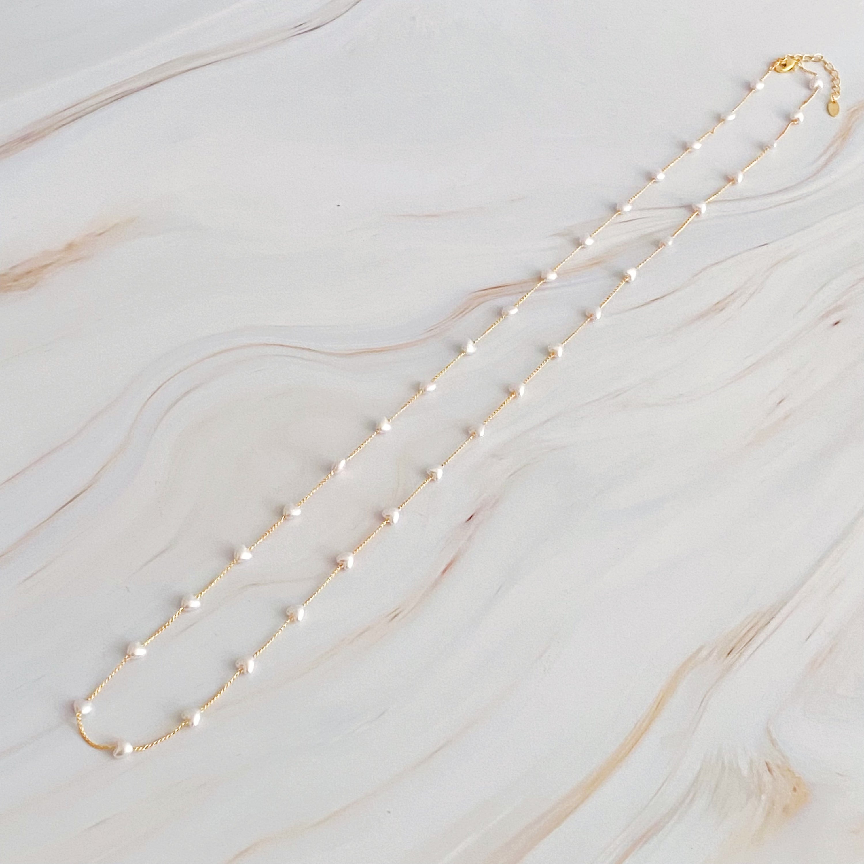 A beautiful Pearl Heart Long Chain Necklace featuring creamy pearl hearts on a 34-inch gold plated chain.