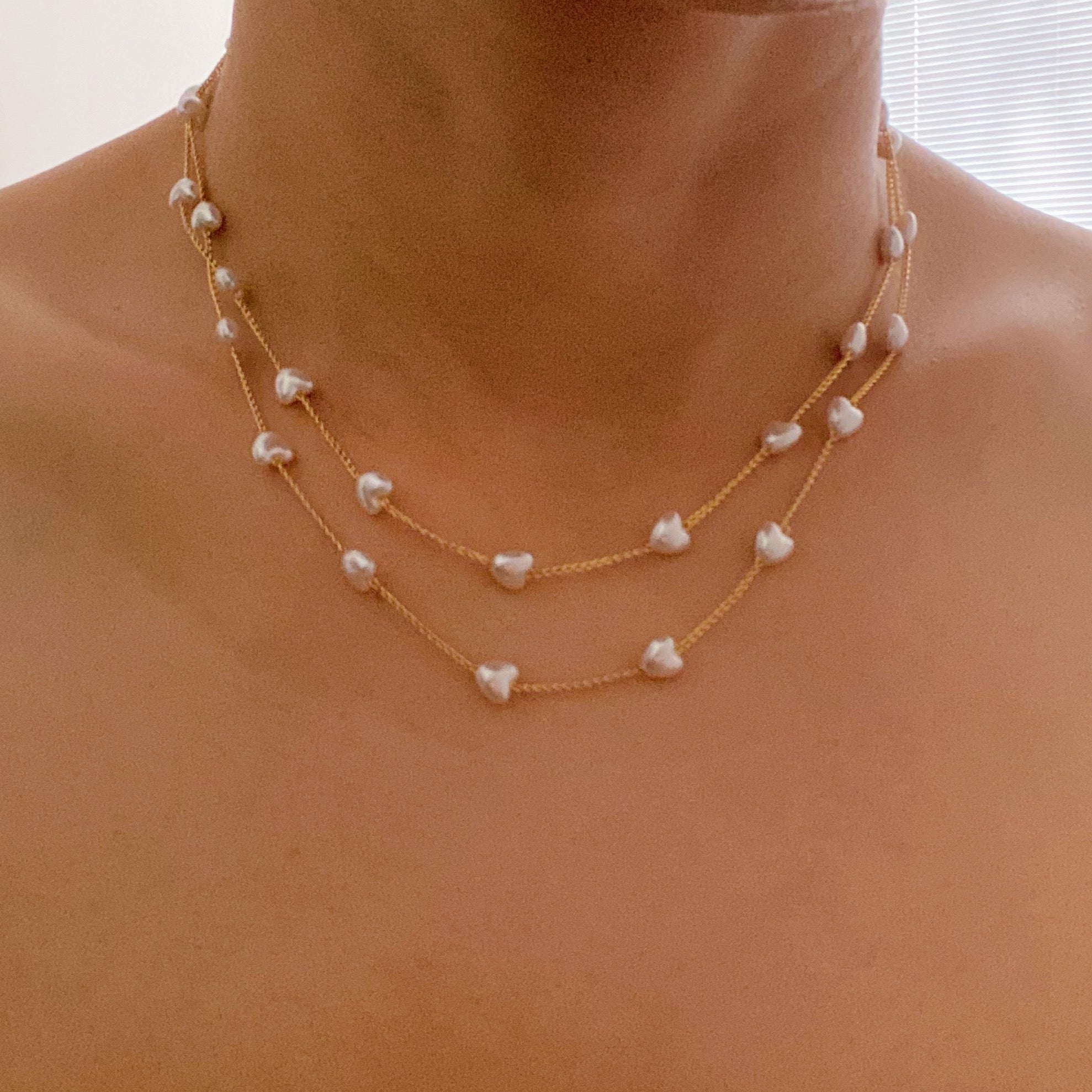 A beautiful Pearl Heart Long Chain Necklace featuring creamy pearl hearts on a 34-inch gold plated chain.