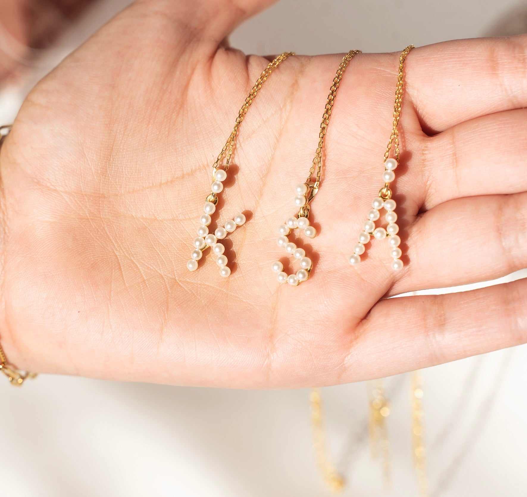 A beautiful PEARL Initial Necklace featuring mini pearls on a 925 sterling silver chain with yellow gold plating.