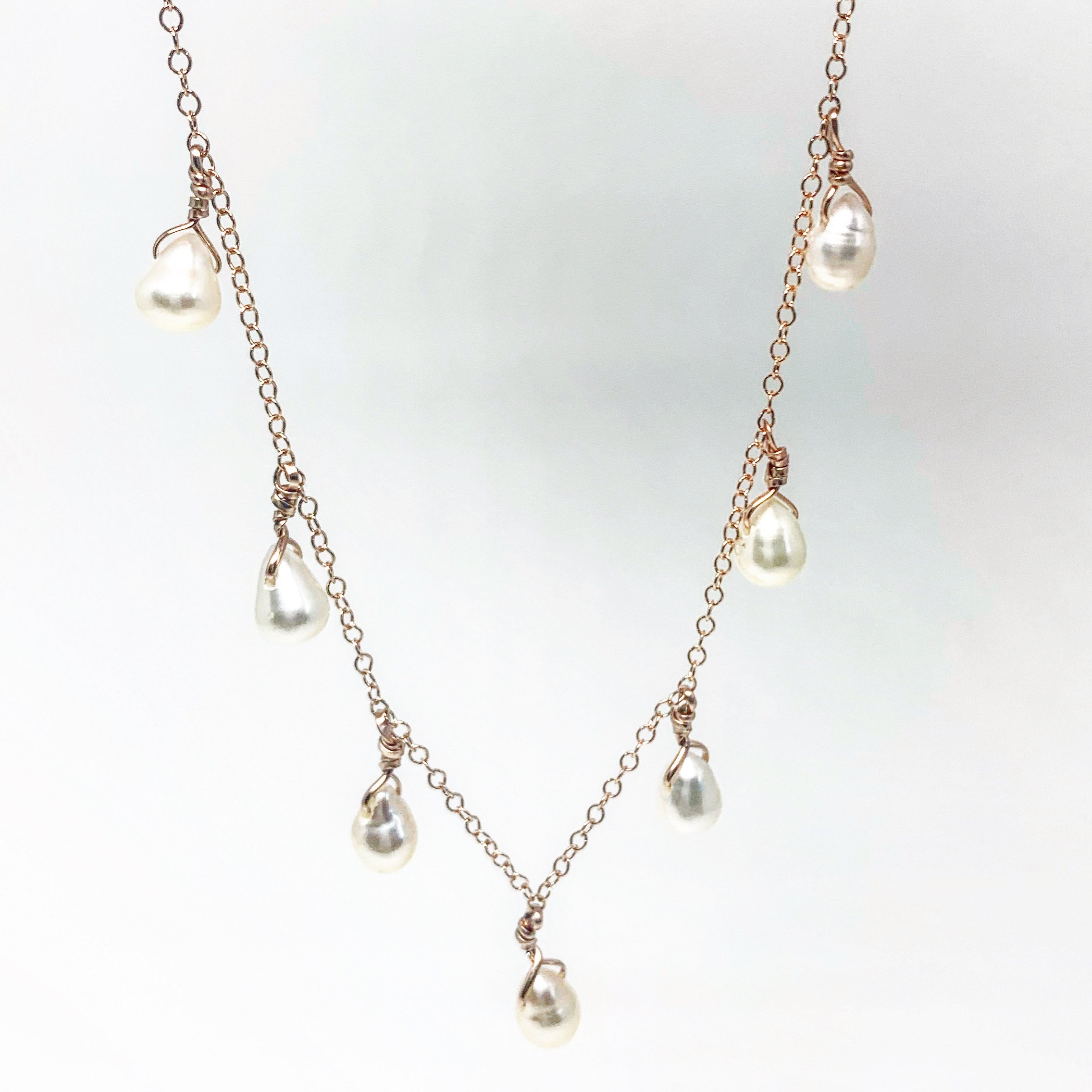 Elegant Pearl Teardrop Necklace featuring seven white freshwater pearls on a sparkling cable chain, available in sterling silver, gold, or rose gold.