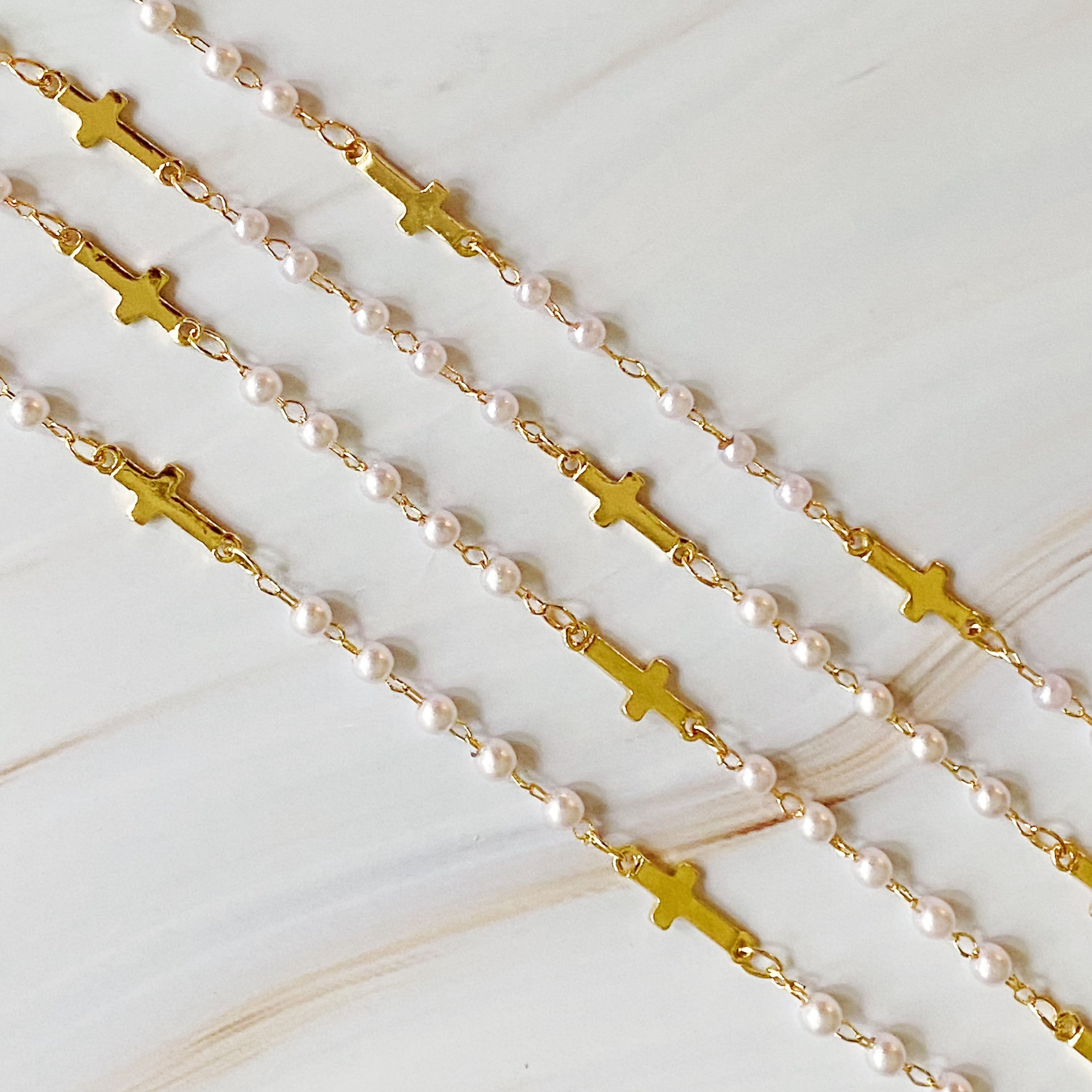 A stylish Pearls And Crosses Long Necklace featuring golden crosses and pearl beads, showcasing its elegant design and versatility.