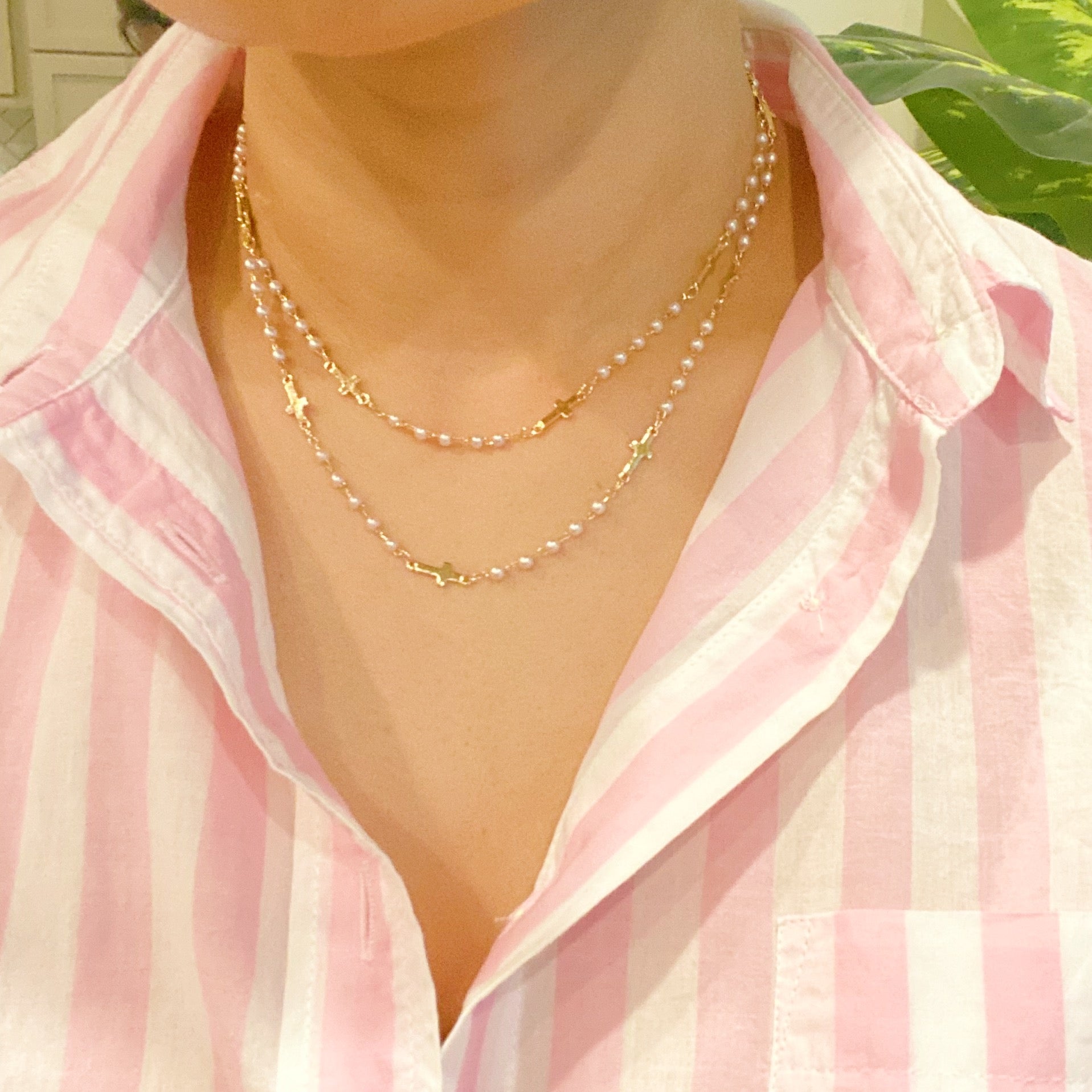 A stylish Pearls And Crosses Long Necklace featuring golden crosses and pearl beads, showcasing its elegant design and versatility.