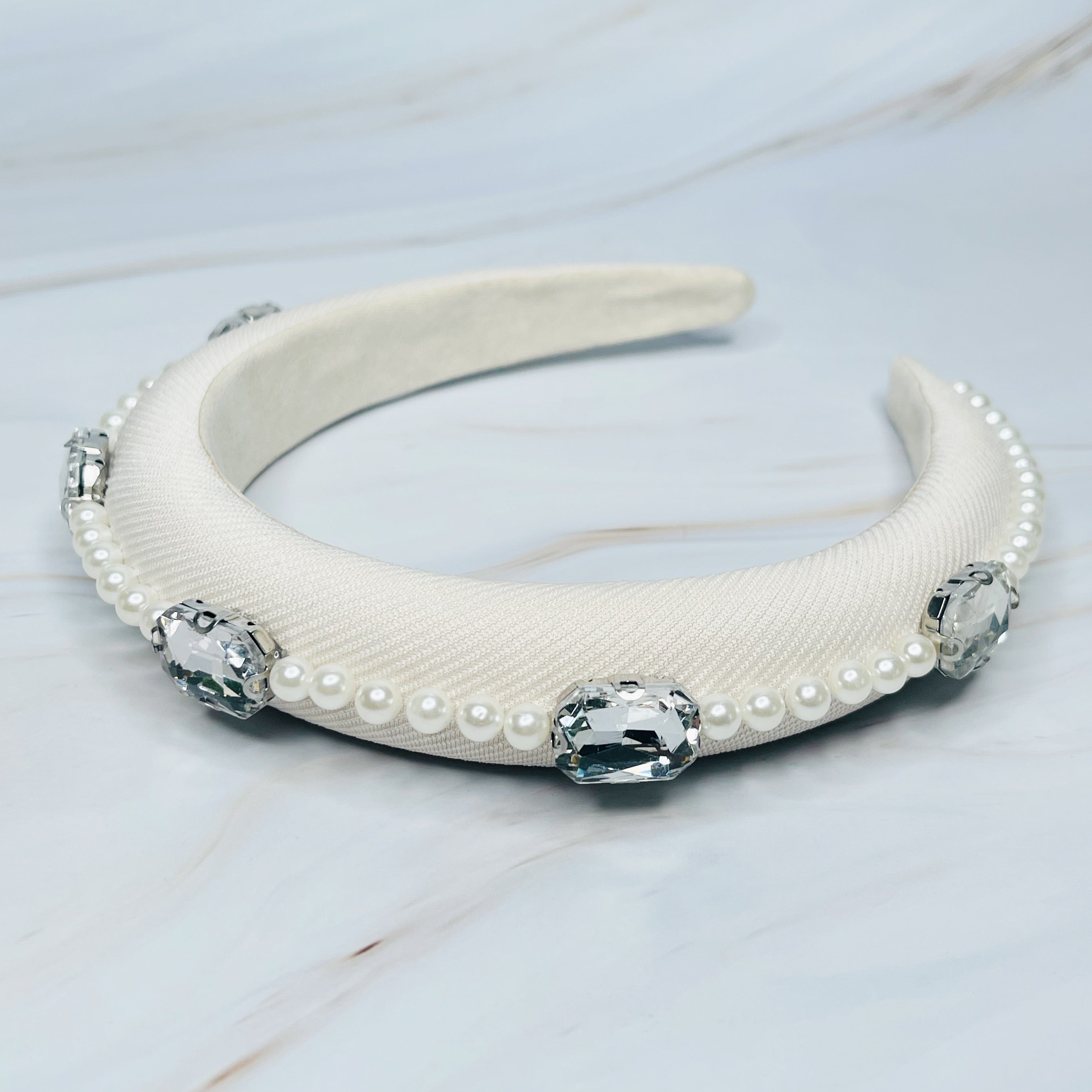 A luxurious Pearls And Jewels Lined Headband featuring elegant pearl and jewel embellishments on a soft material.