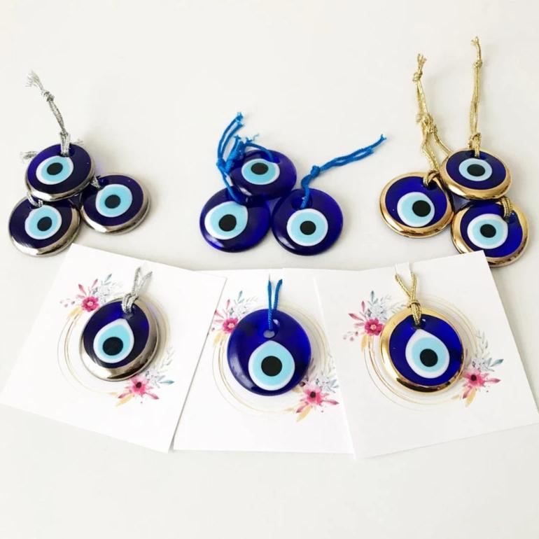 A collection of 50 personalized evil eye wedding gifts featuring gold, silver, and blue beads, beautifully arranged with custom cards.