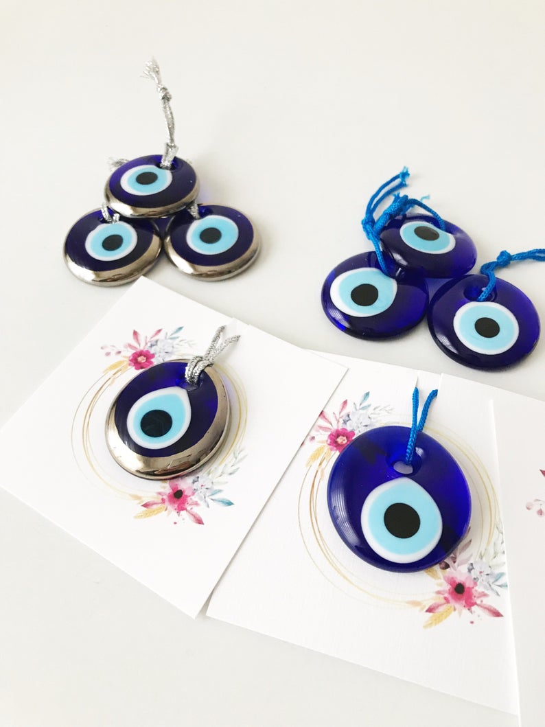 A collection of 50 personalized evil eye wedding gifts featuring gold, silver, and blue beads, beautifully arranged with custom cards.