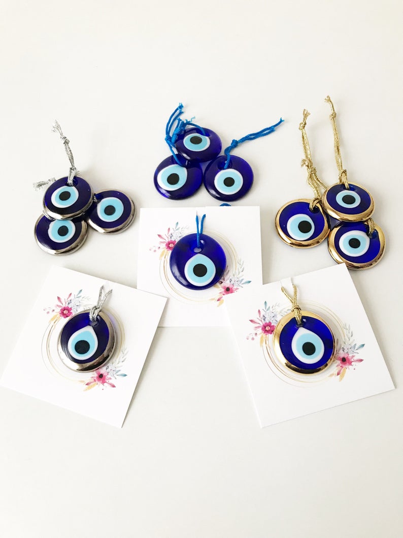 A collection of 50 personalized evil eye wedding gifts featuring gold, silver, and blue beads, beautifully arranged with custom cards.