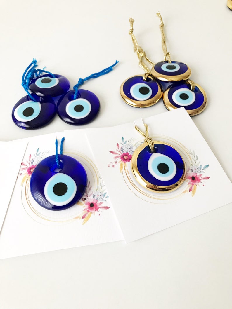 A collection of 50 personalized evil eye wedding gifts featuring gold, silver, and blue beads, beautifully arranged with custom cards.