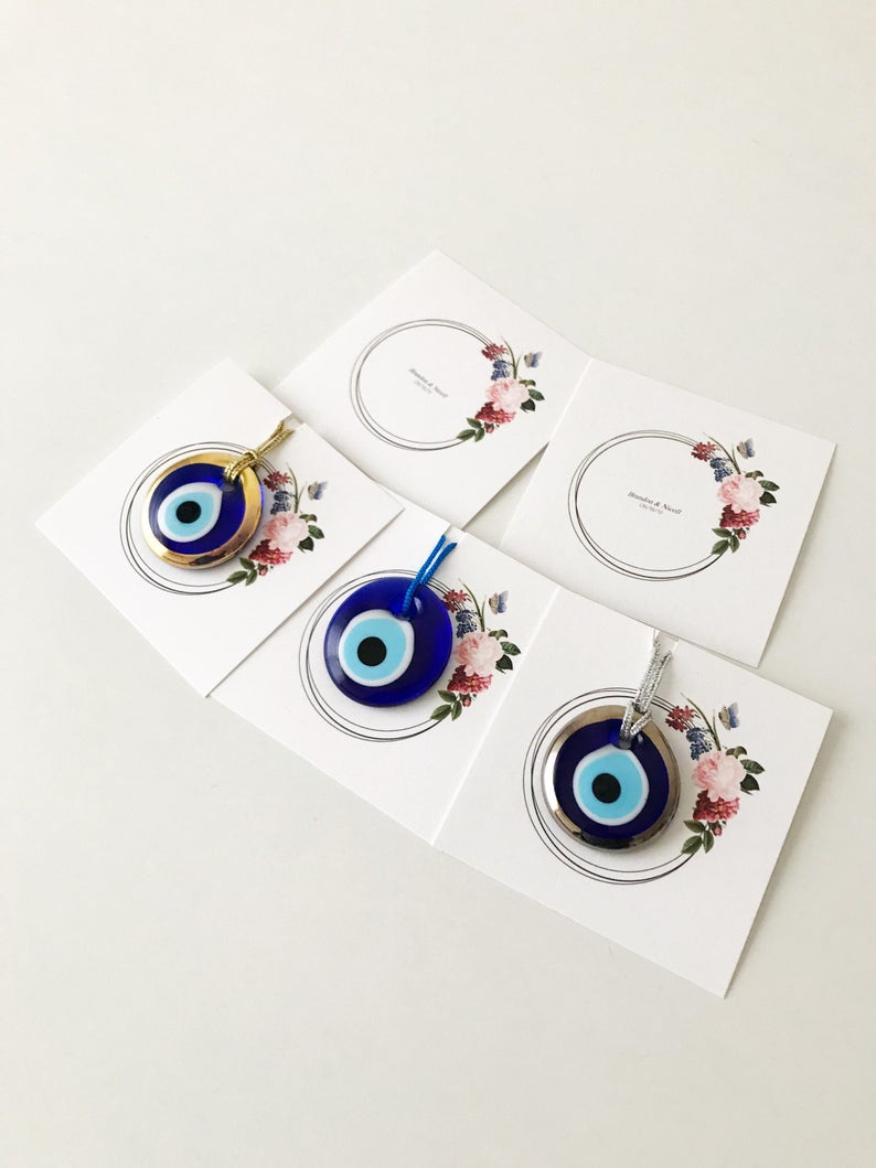 A collection of 10 handmade glass evil eye beads with personalized cards, featuring blue, gold, and silver colors, perfect for wedding favors.