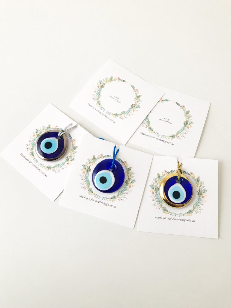 A collection of 10 handmade glass evil eye beads with personalized cards, featuring blue, gold, and silver colors, perfect for wedding favors.