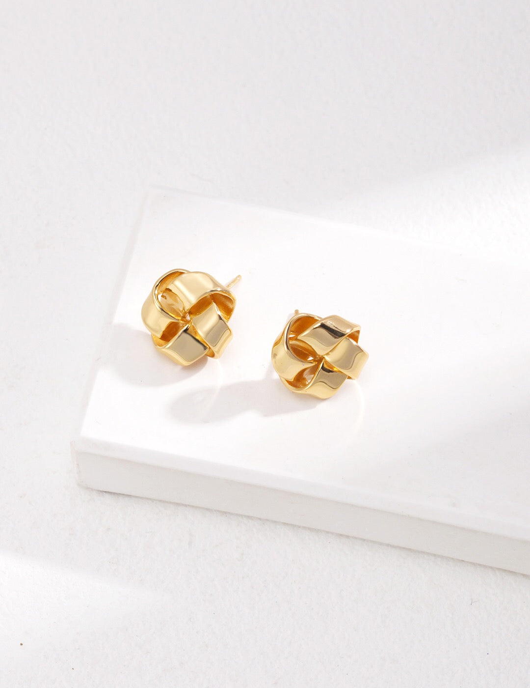 A pair of Petite Love Knot Stud Earrings made of gold vermeil, showcasing a delicate knot design, perfect for everyday wear.