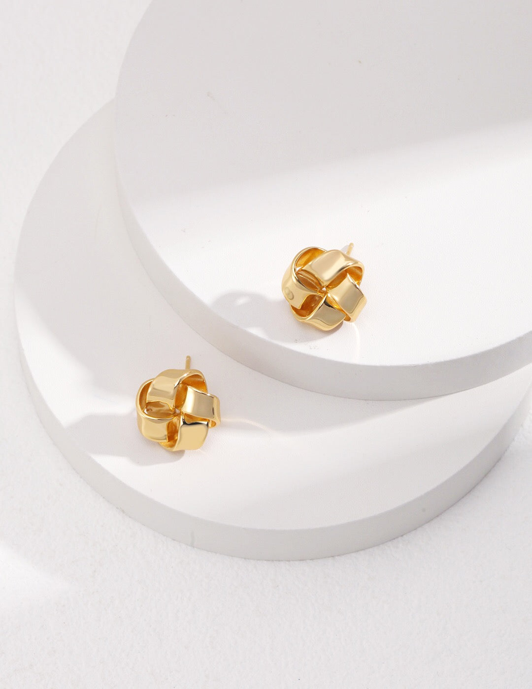 A pair of Petite Love Knot Stud Earrings made of gold vermeil, showcasing a delicate knot design, perfect for everyday wear.