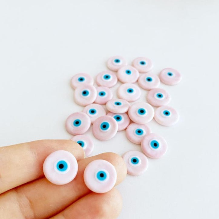 A collection of pink Murano glass evil eye cabochons, each 15mm in diameter, showcasing intricate designs and vibrant colors.