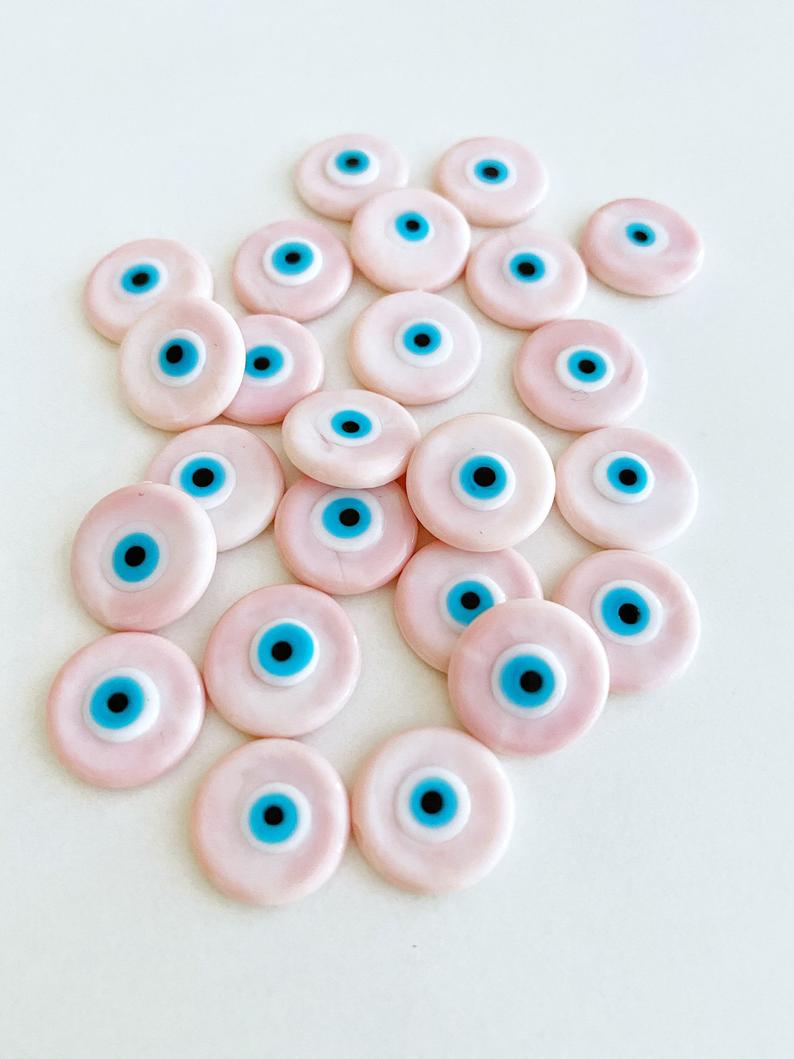 A collection of pink Murano glass evil eye cabochons, each 15mm in diameter, showcasing intricate designs and vibrant colors.